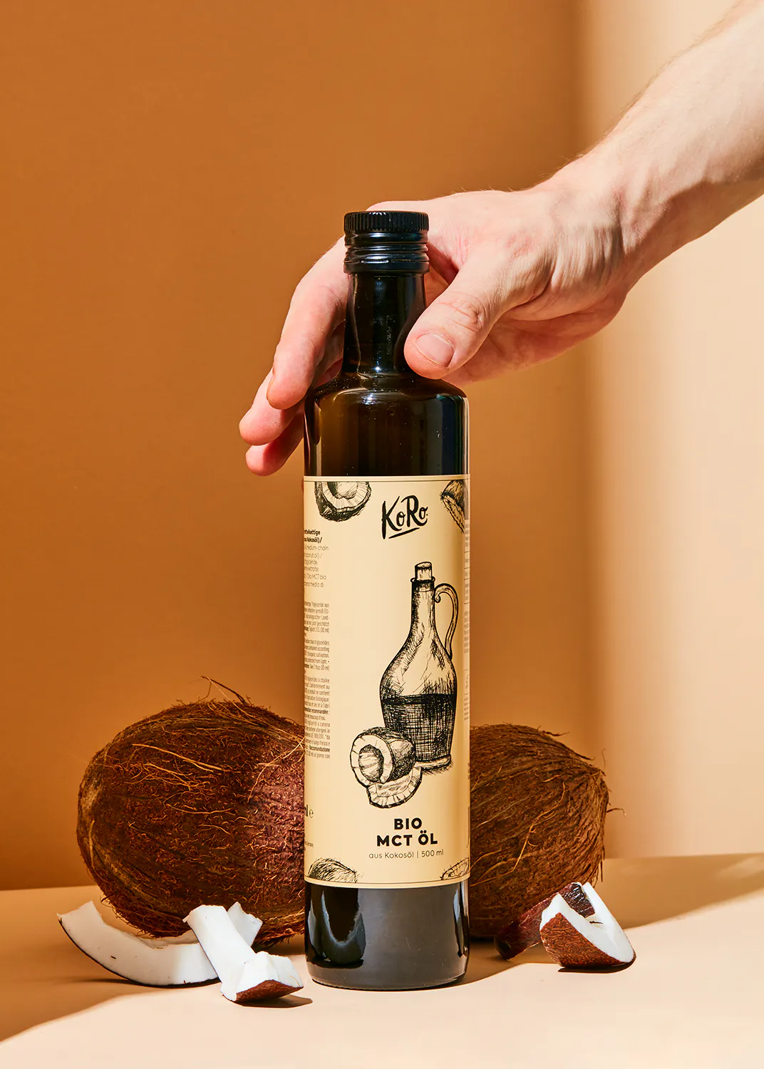 une main tient une bouteille d' huile de coco bio