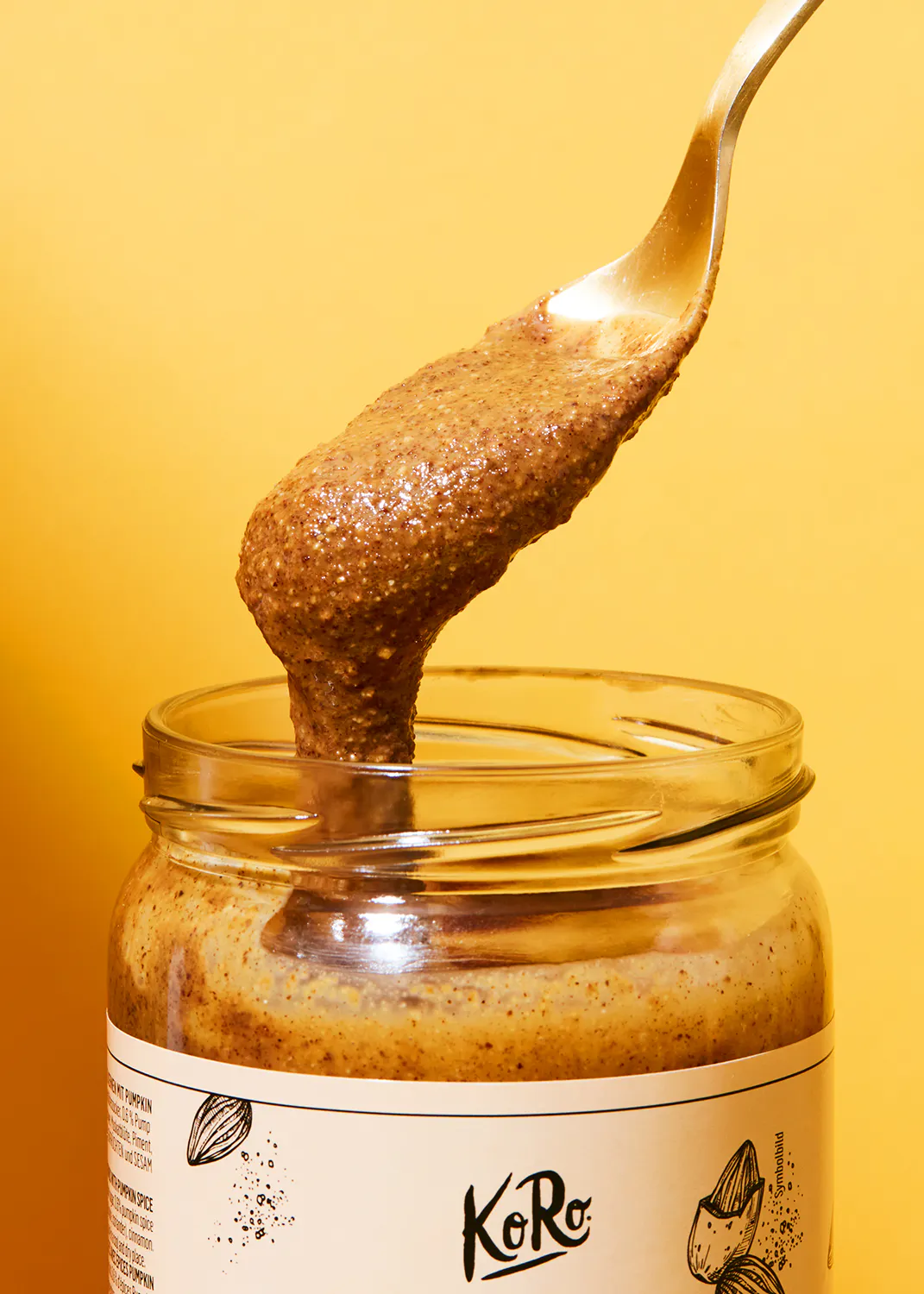 ein Löffel hält etwas Erdnussbutter aus einem Glas