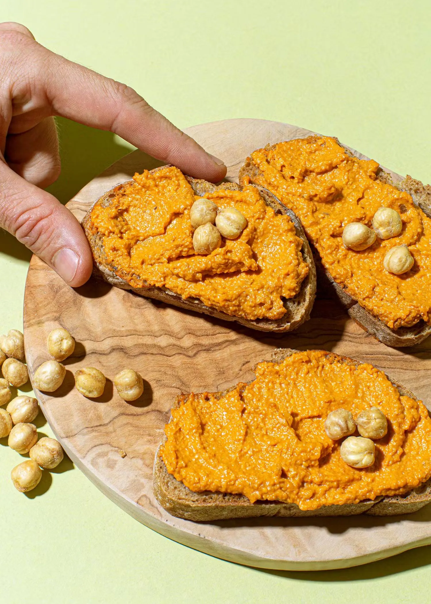 three slices of bread with hummus and nuts on them