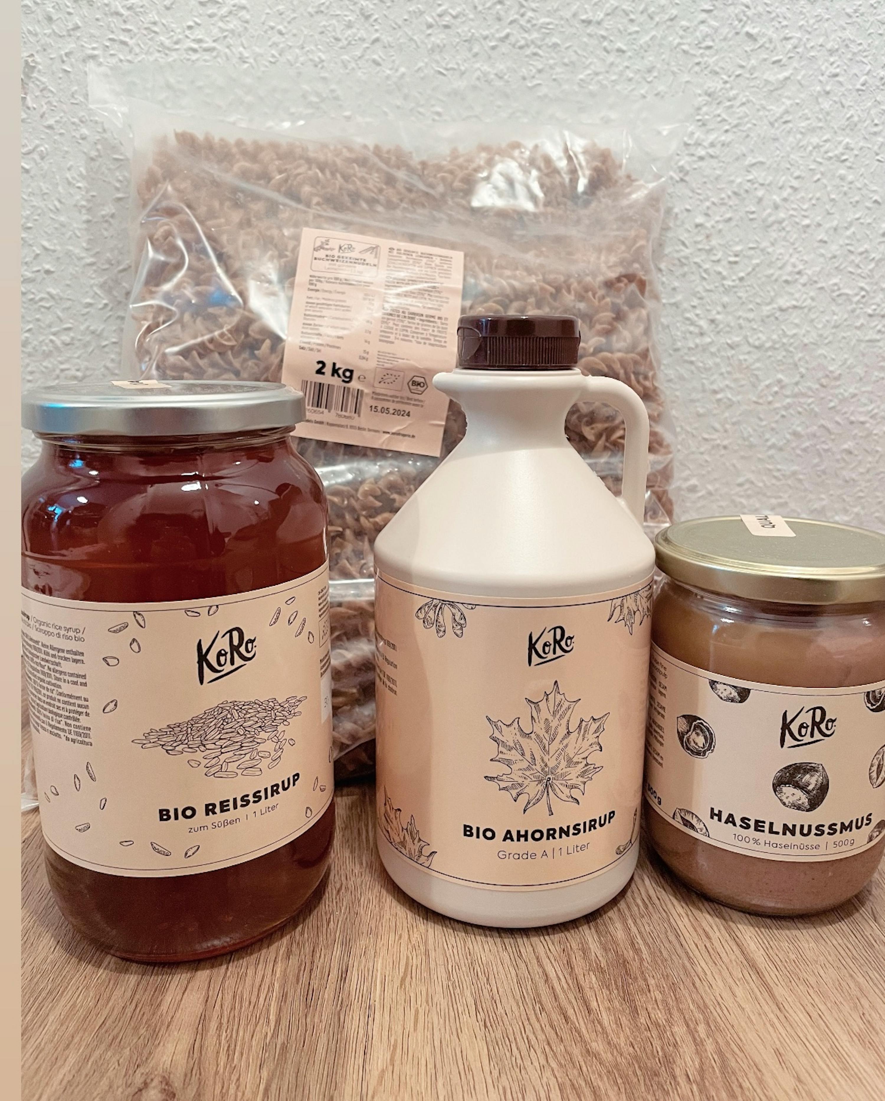 a jar of bio reissirup sits next to a jar of bio ahornsirup and a jar of haselnussolie