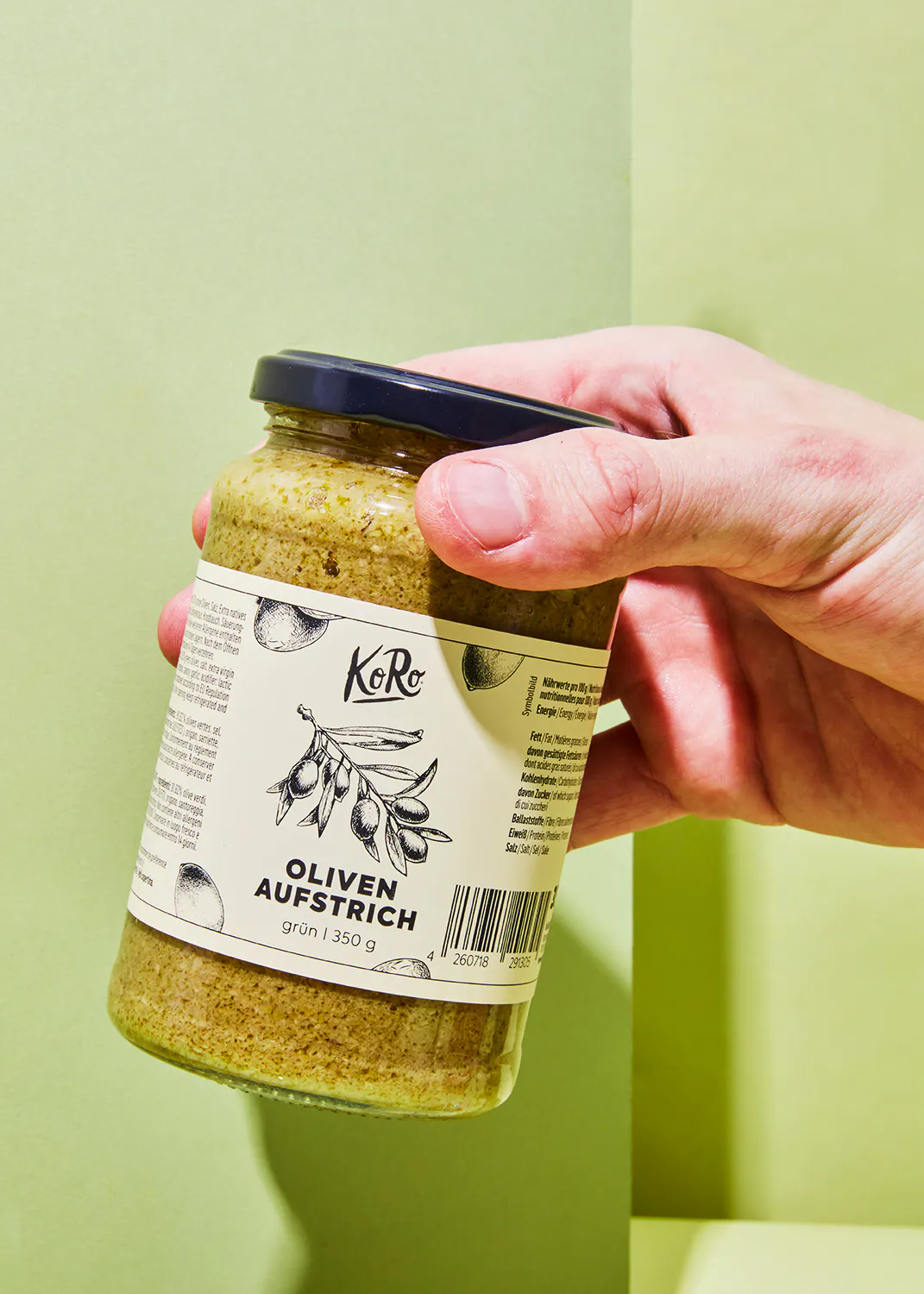 une personne tient un bocal d' oliven aufstrich