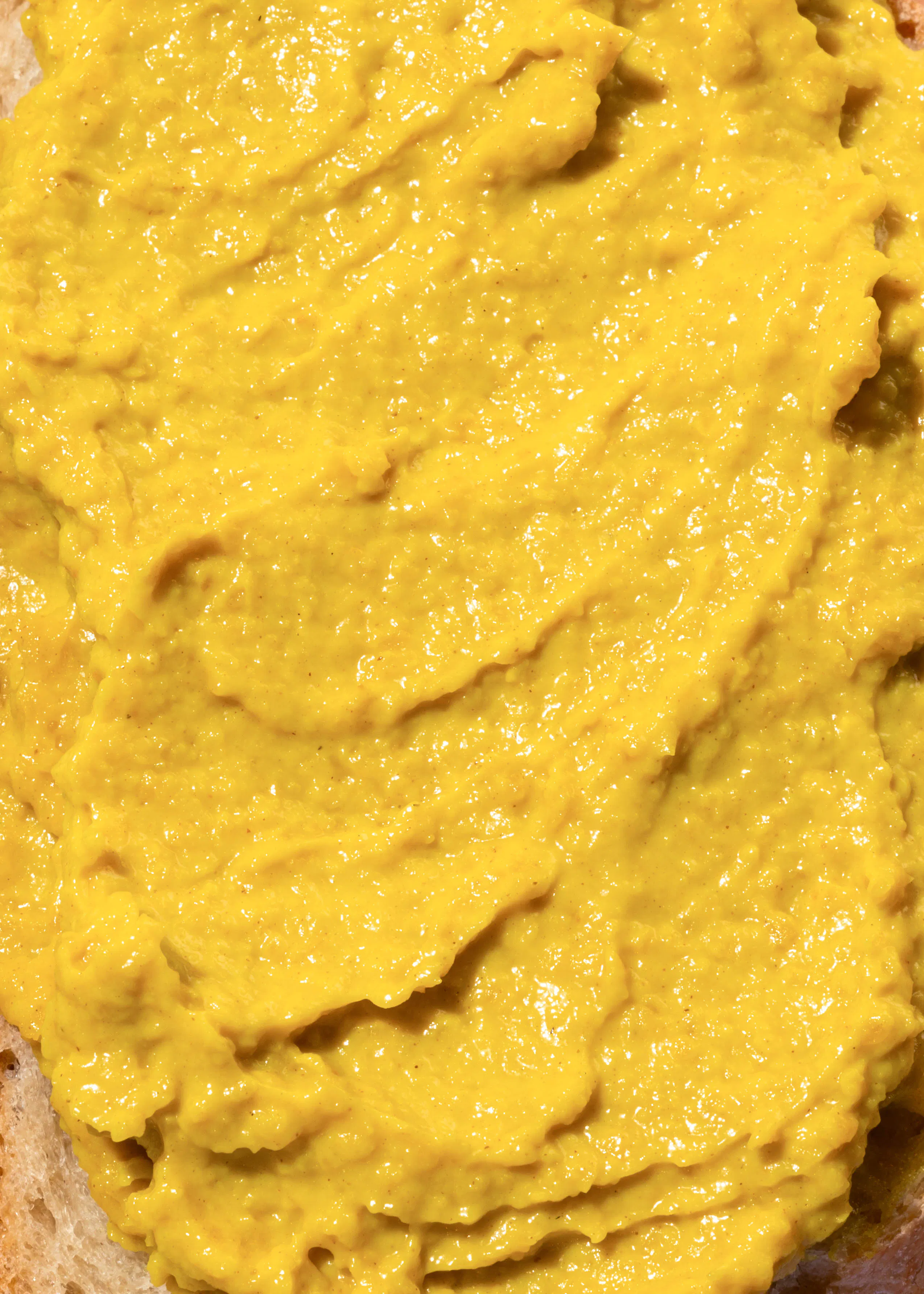 un gros plan d' une sauce jaune sur un morceau de pain