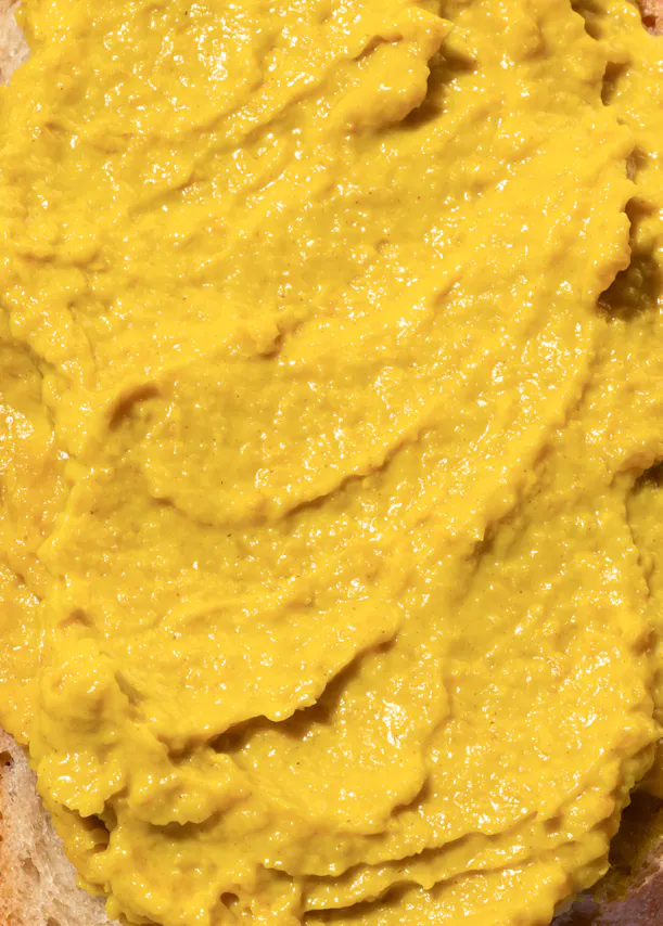 un gros plan d' une sauce jaune sur un morceau de pain