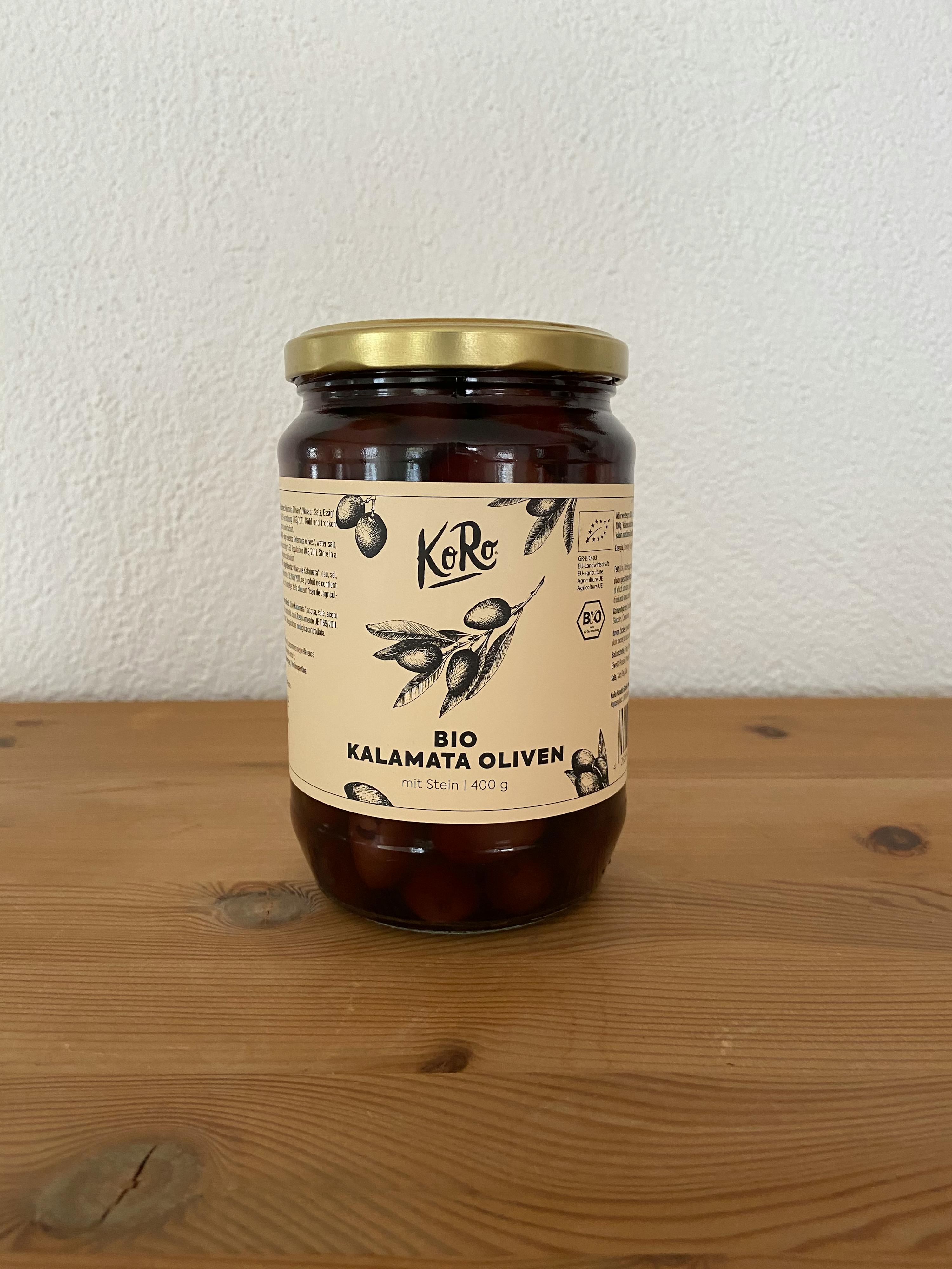 ein Glas bio kalamata Oliven steht auf einem Holztisch