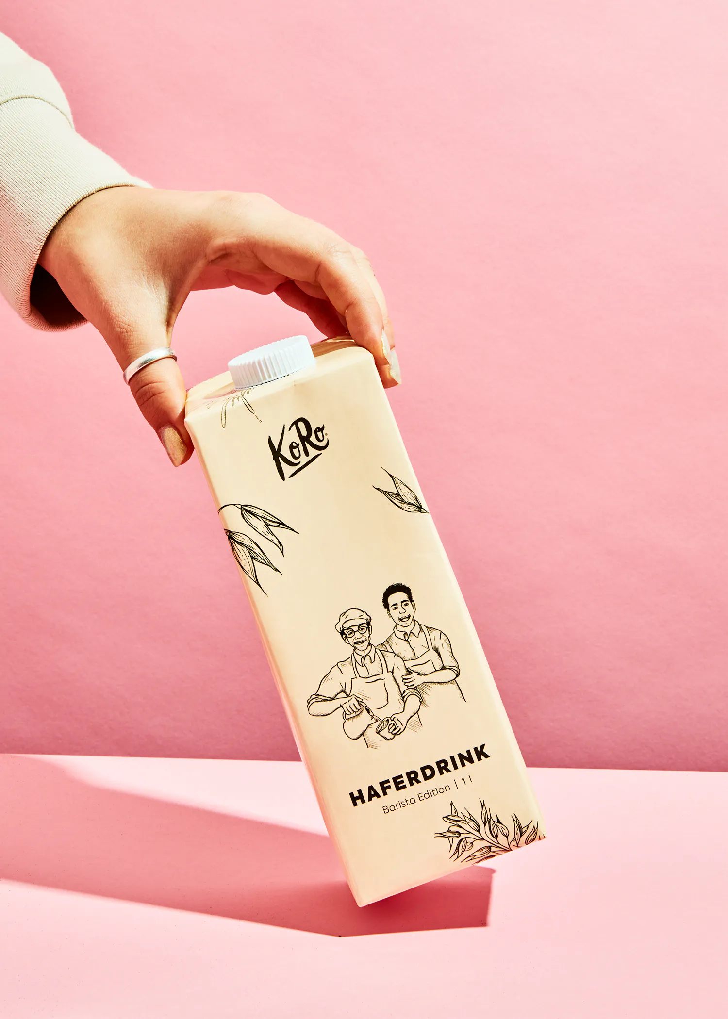 une personne tient une boîte de boisson à l' avoine sur fond rose