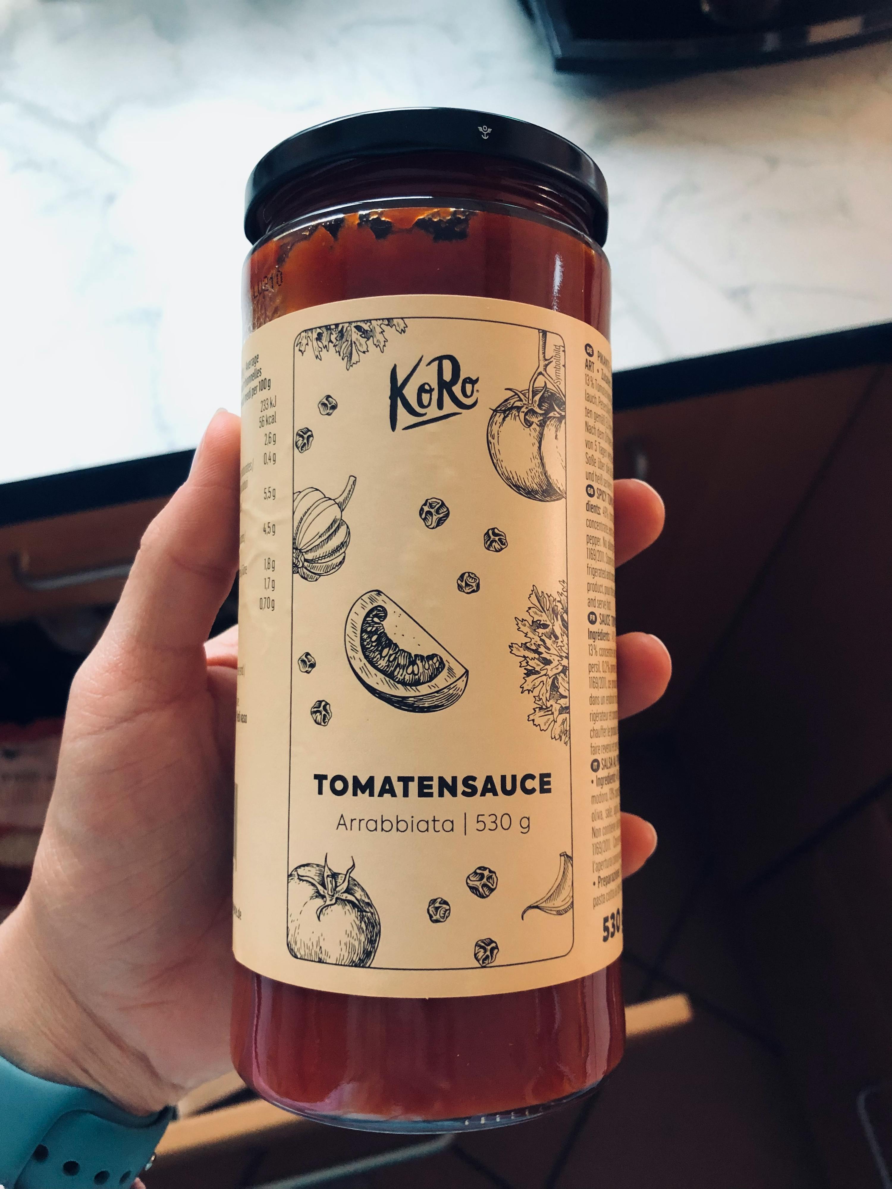 a person is holding a jar of tomato sauce with a white label