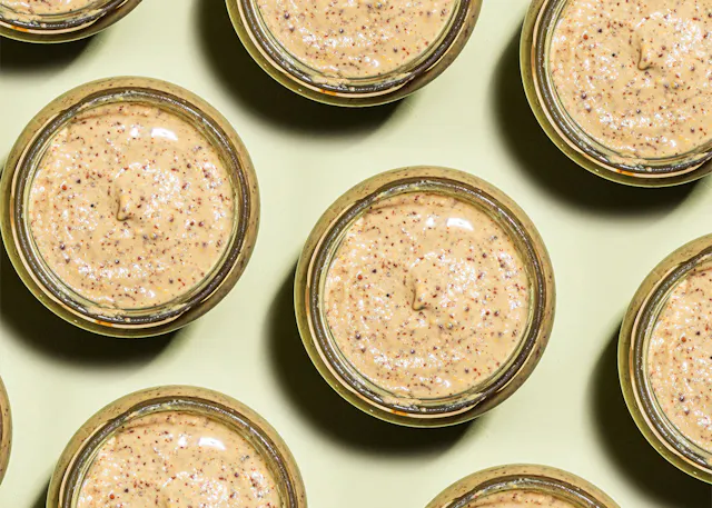 a row of jars filled with a creamy sauce on a green surface