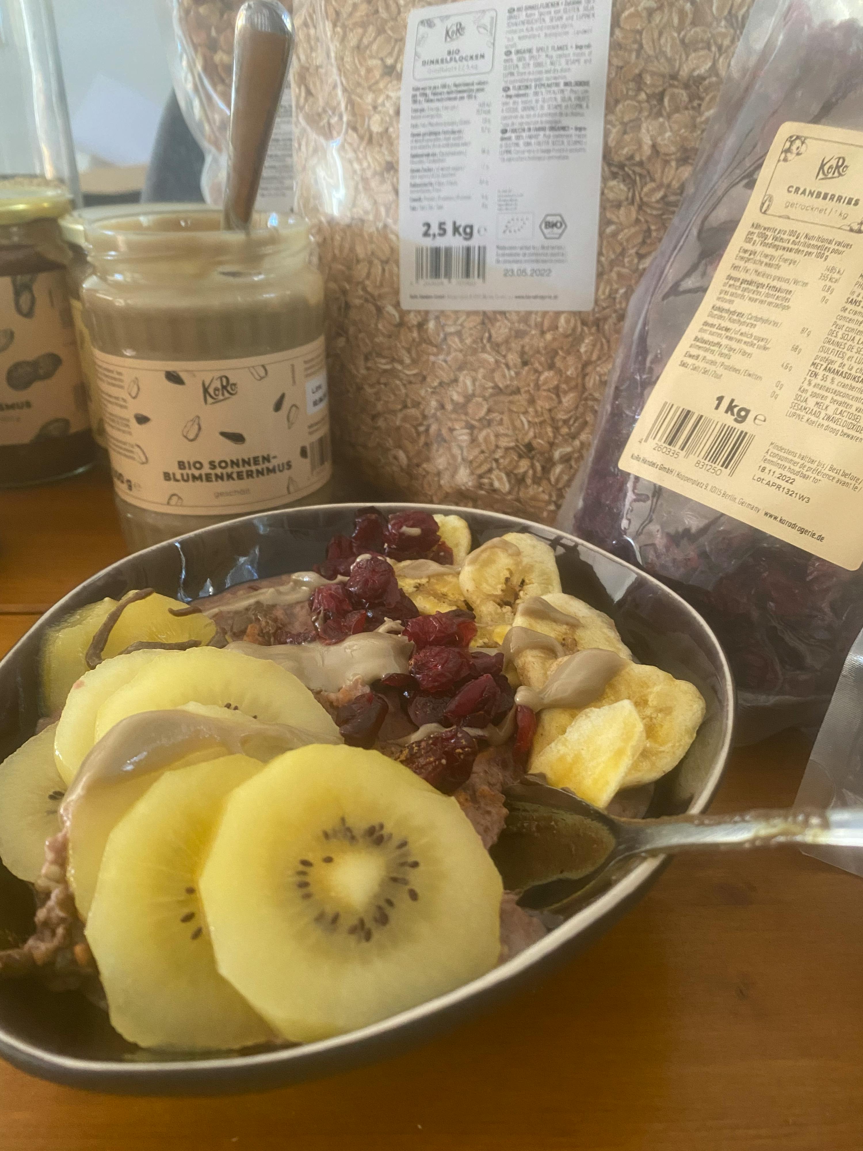 un bol de nourriture avec des kiwis et des bananes à côté d' une bouteille de beurre d' arachide bio