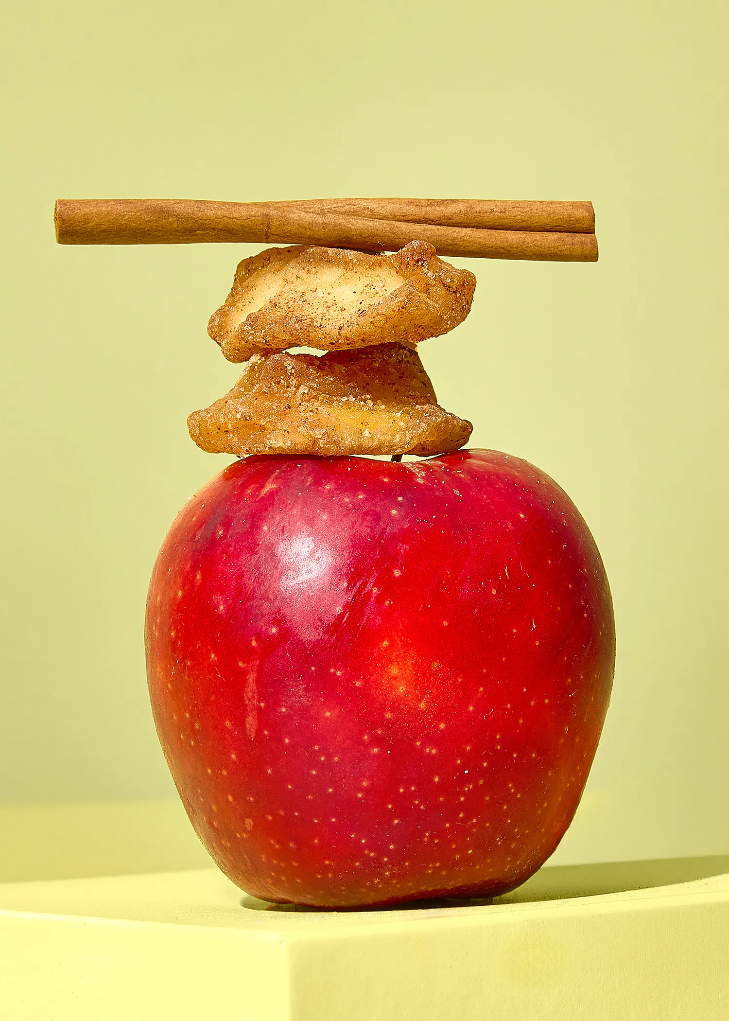 ein roter Apfel mit getrockneten Äpfeln und Zimtstangen darauf gestapelt