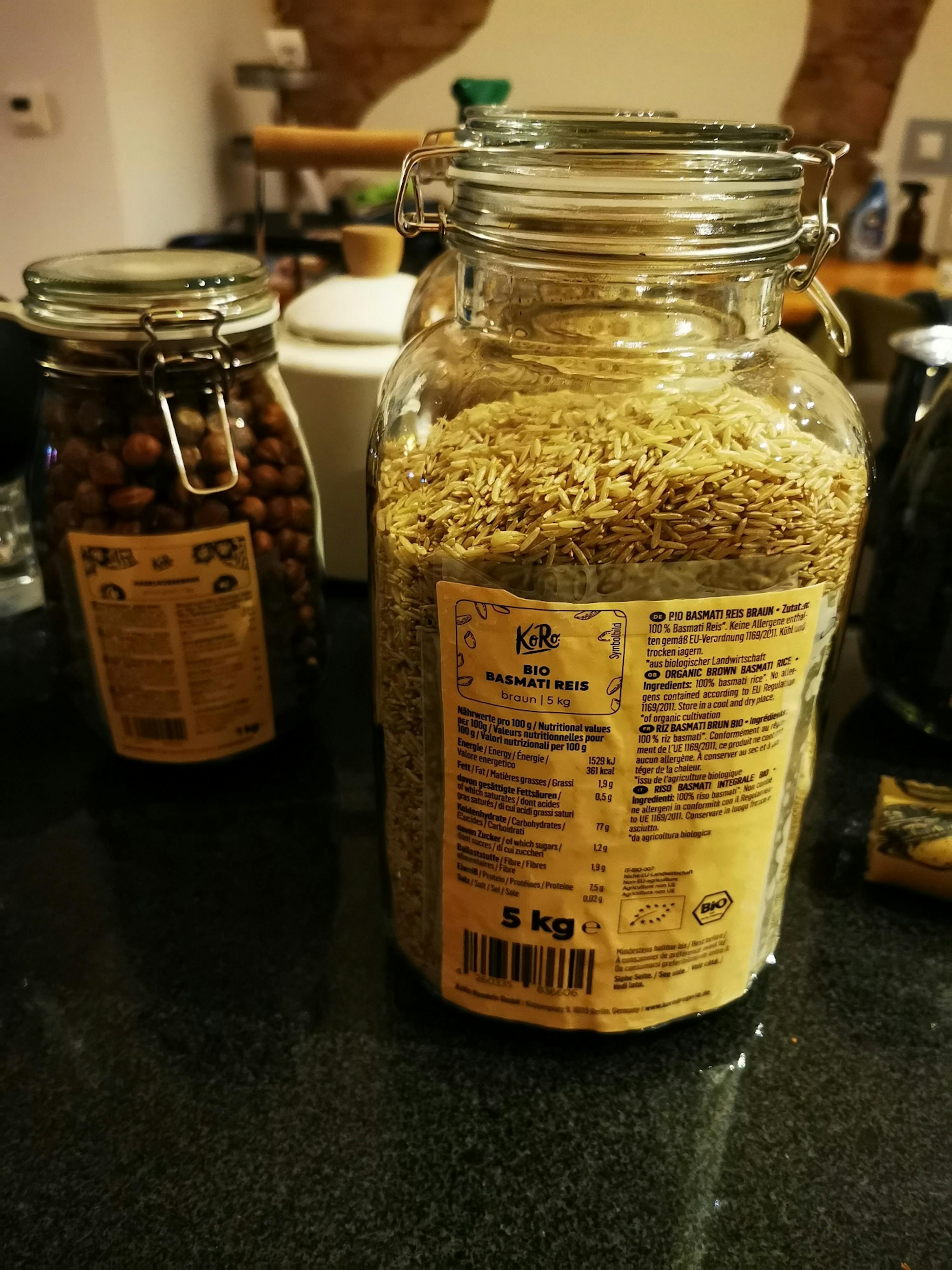 un barattolo di riso basmati è seduto su un tavolo accanto a un barattolo di noci
