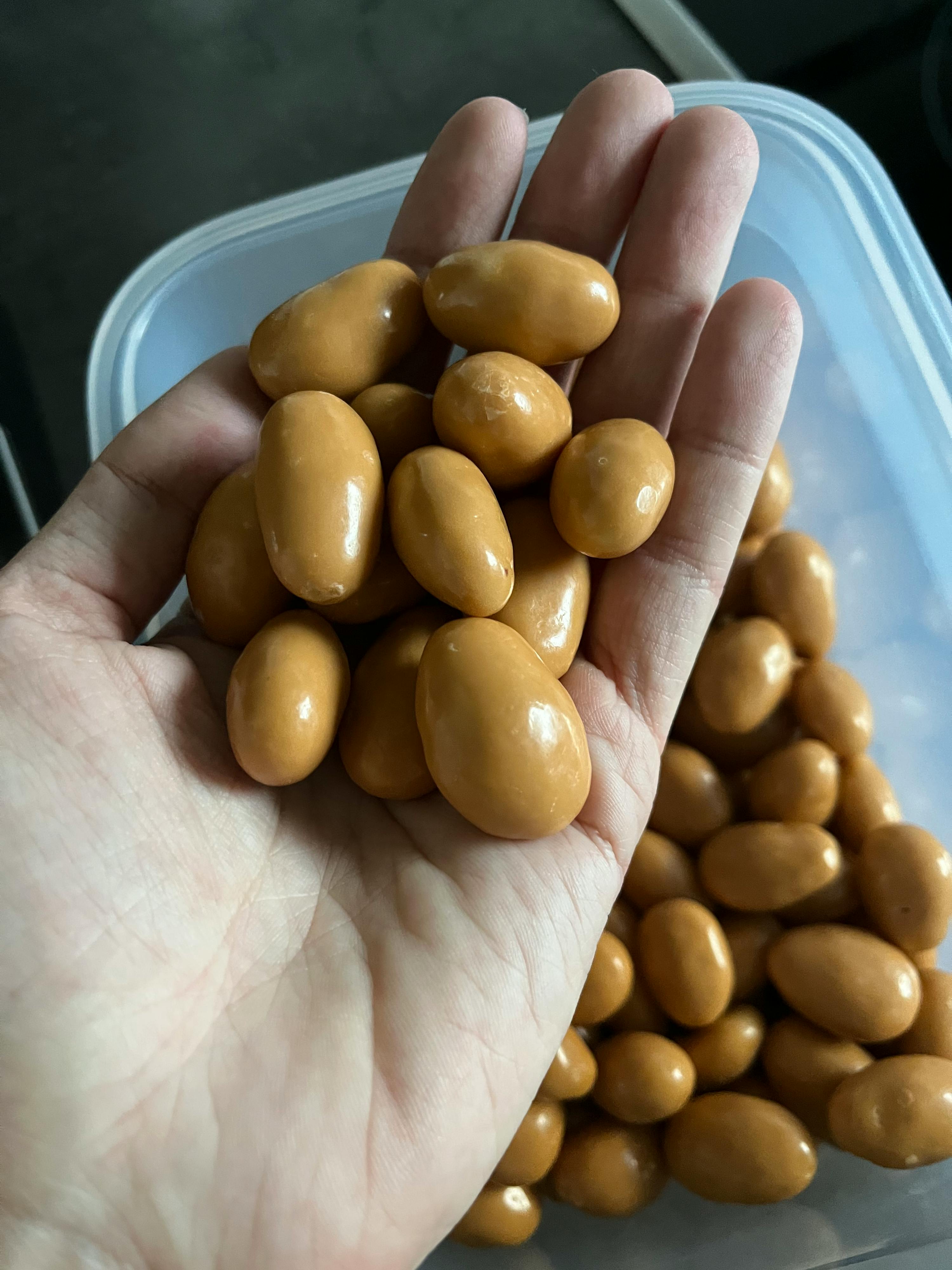 une personne tient un tas de noix enrobées de caramel