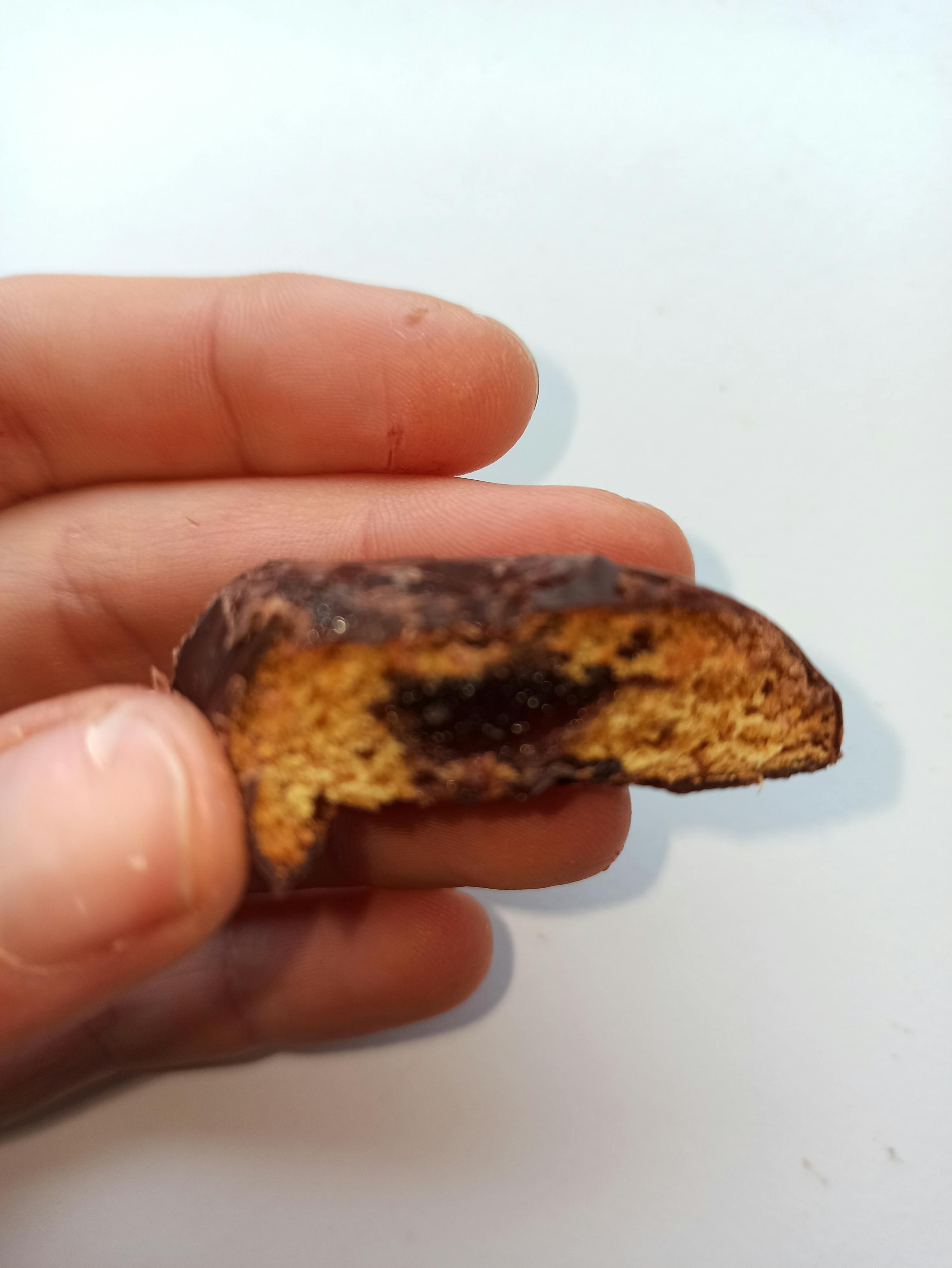 a person is holding a piece of chocolate covered bread with a bite taken out of it