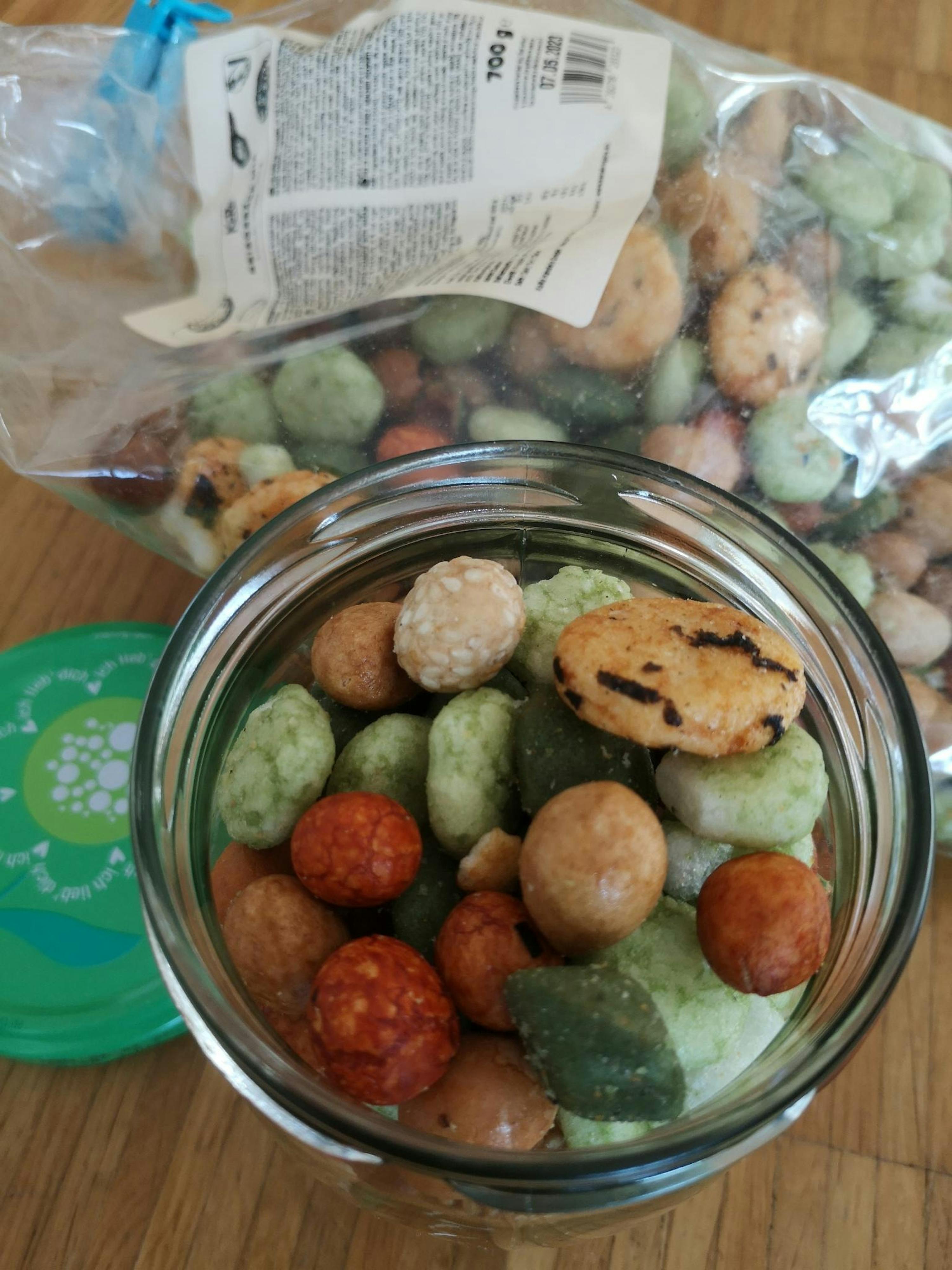 a glass bowl filled with nuts next to a bag of nuts