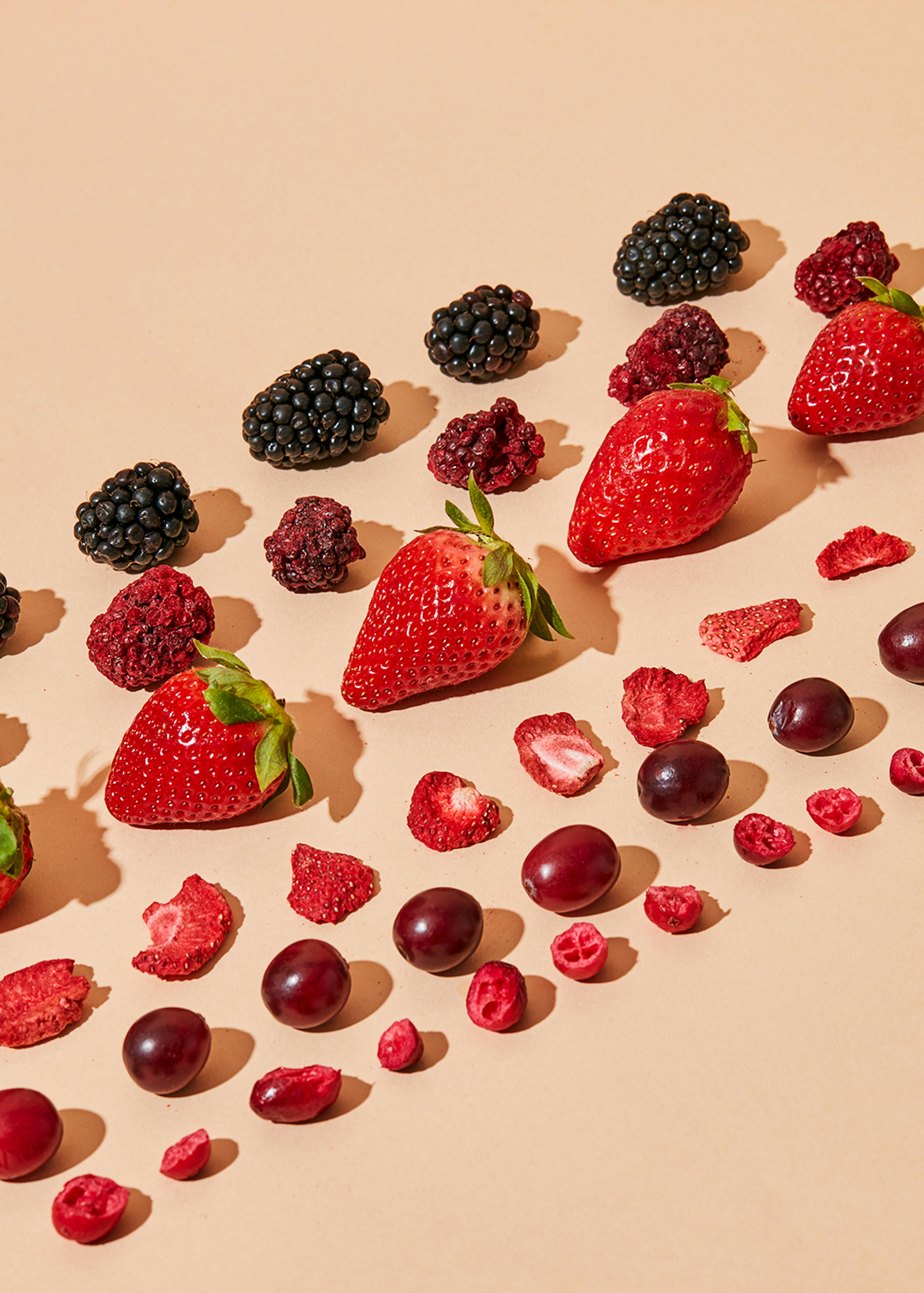 strawberries blackberries grapes and cranberries arranged in a row