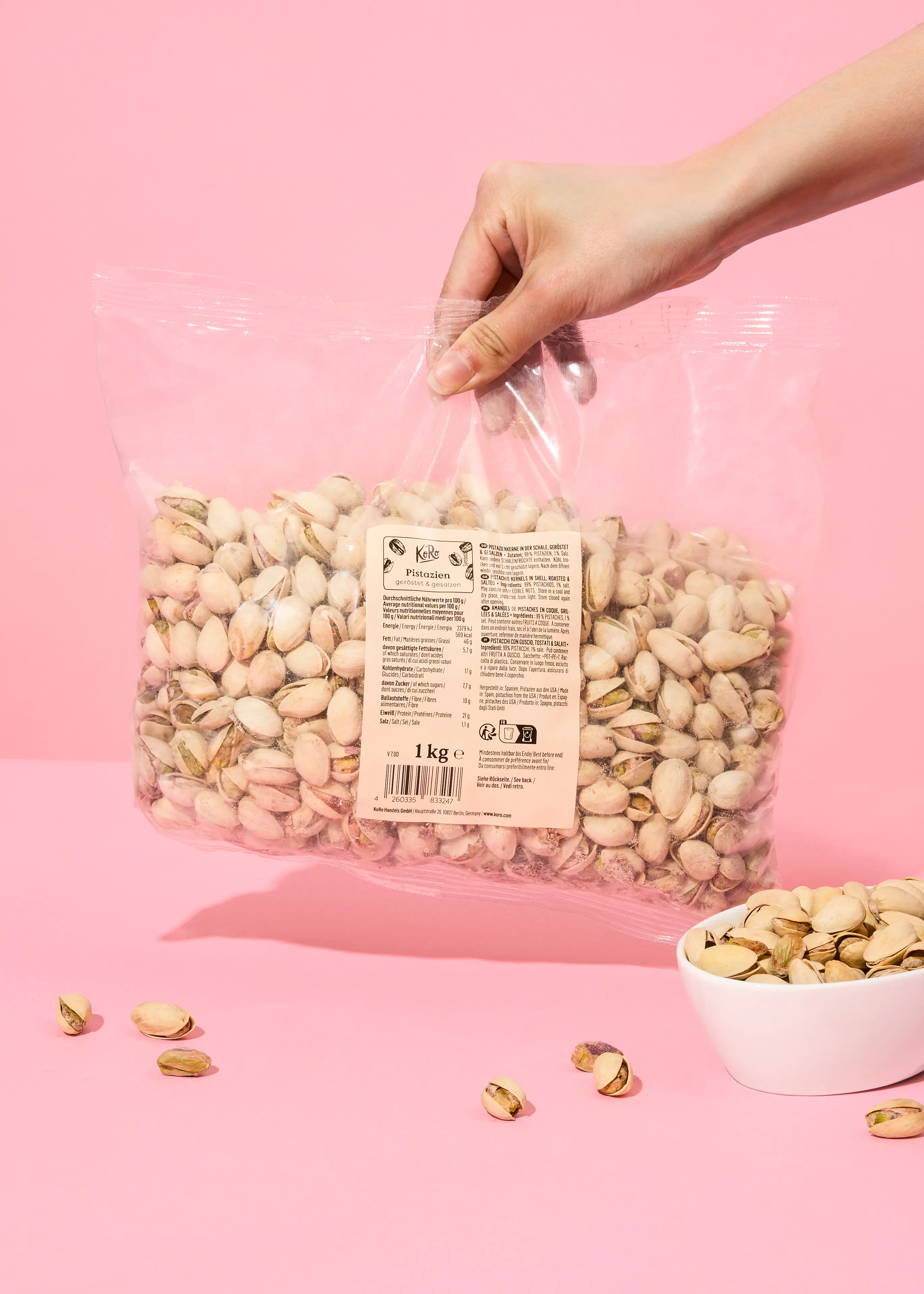 une personne tient un sac de pistaches sur un fond rose