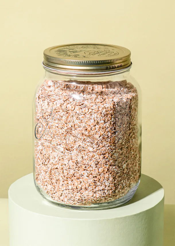 un bocal en verre rempli de flocons d' avoine avec un couvercle en métal