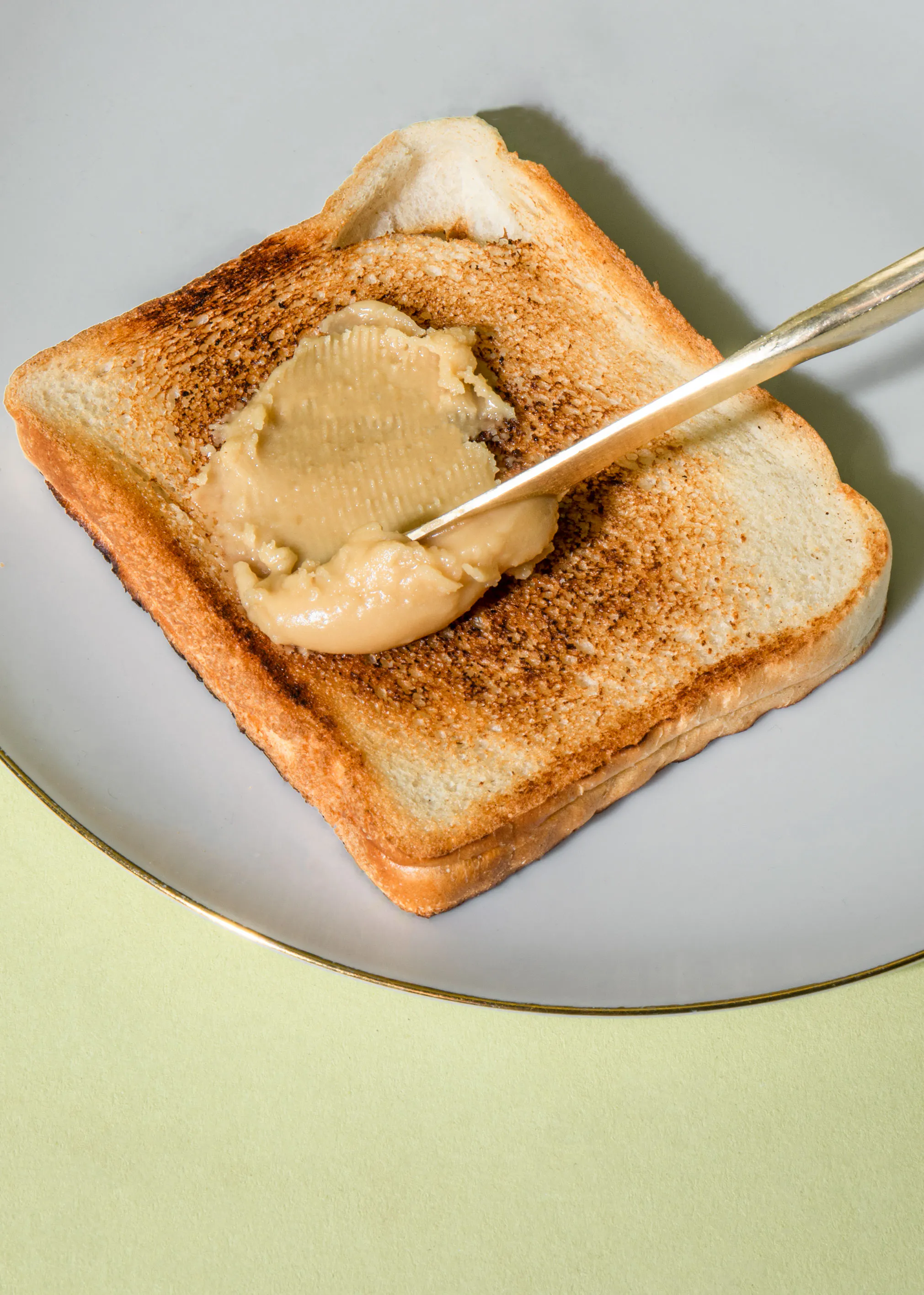 peanut butter is being spread on a piece of toasted bread