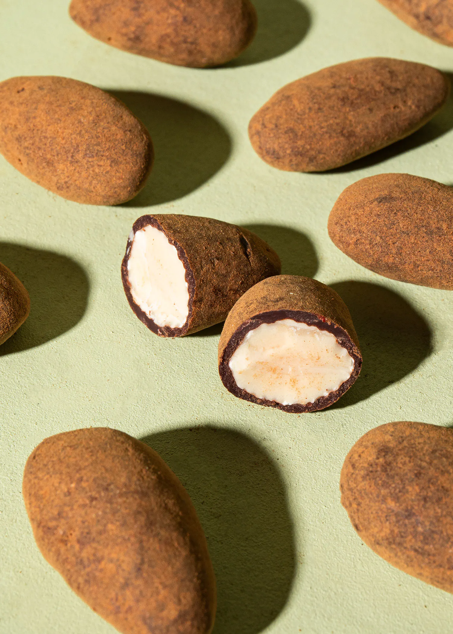 eine Gruppe von Schokoladen-Mandeln auf einer grünen Oberfläche