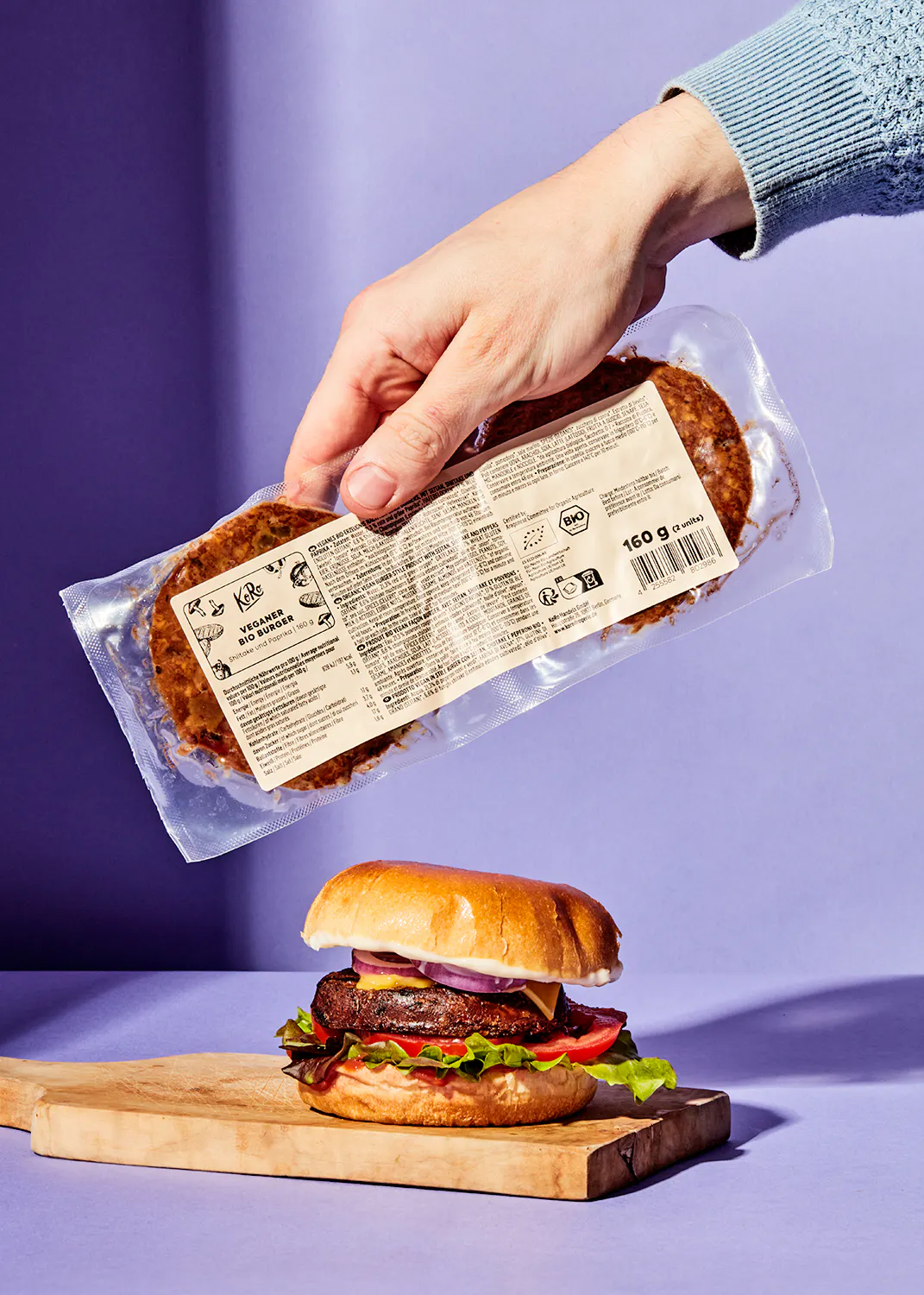 eine Person hält einen Plastikbeutel mit einem veganen Burger darin