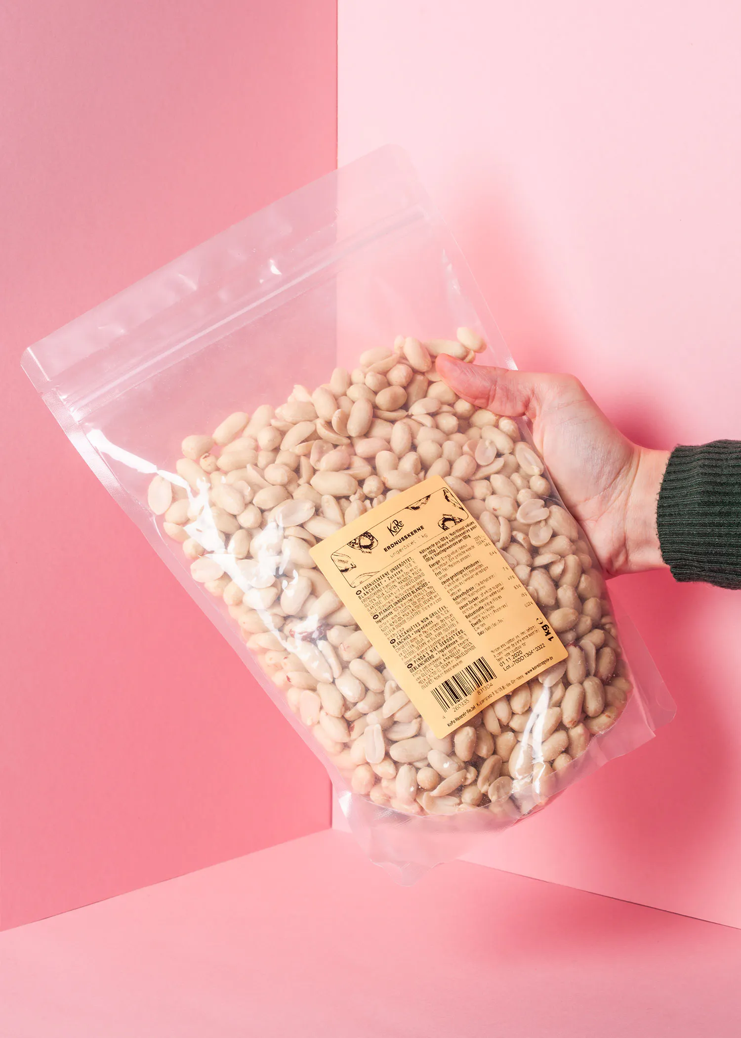 eine Person hält eine Plastiktüte mit Erdnüssen in der Hand