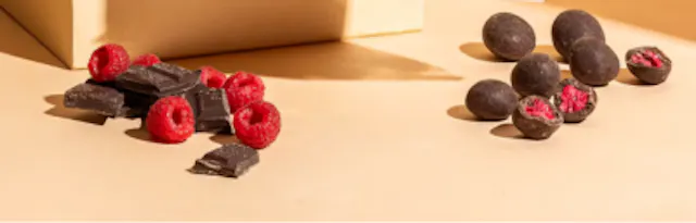 ein Haufen Himbeeren neben einem Haufen Schokoladenkugeln