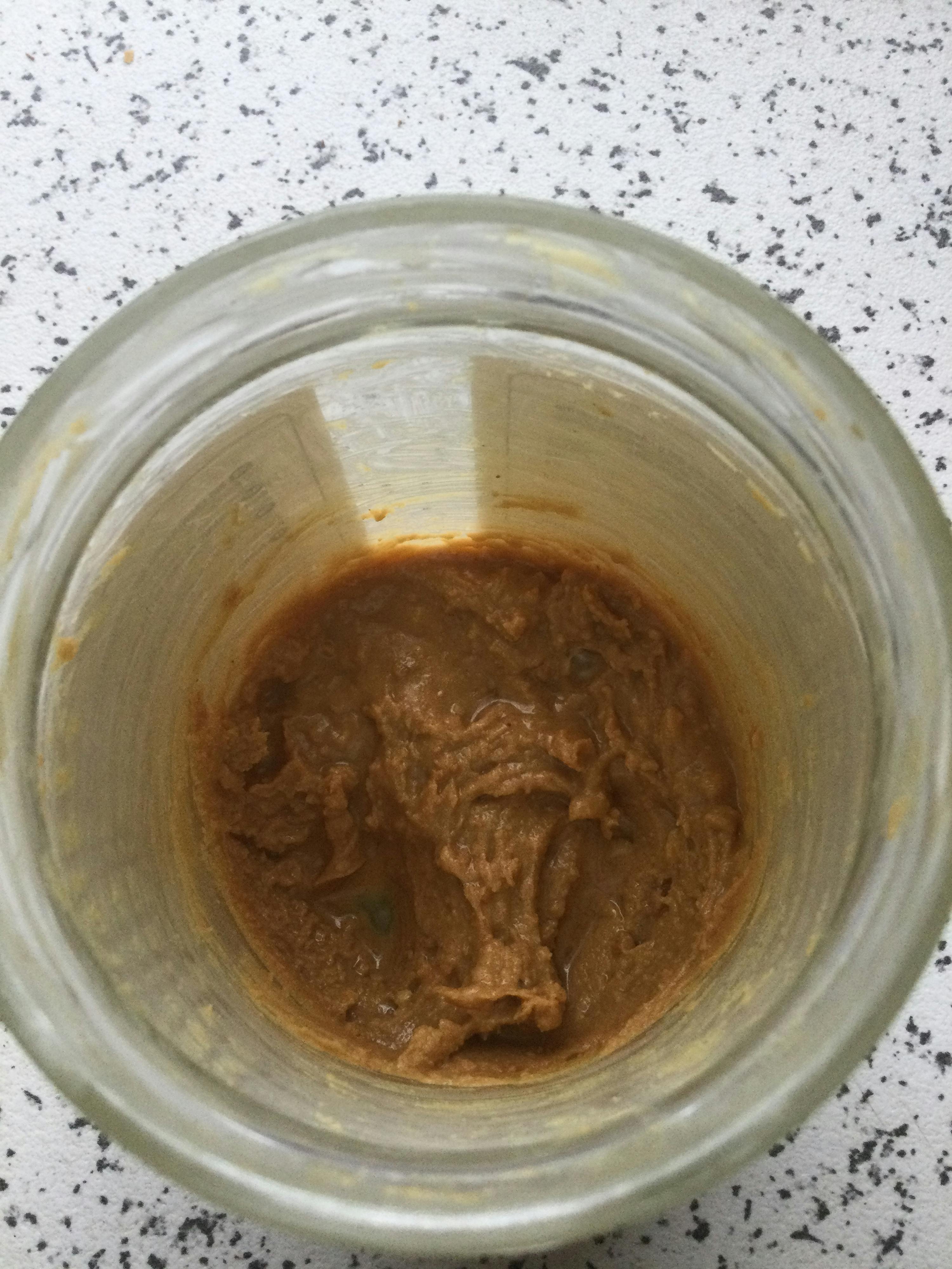 ein Glas mit brauner Flüssigkeit darin steht auf einem Tisch