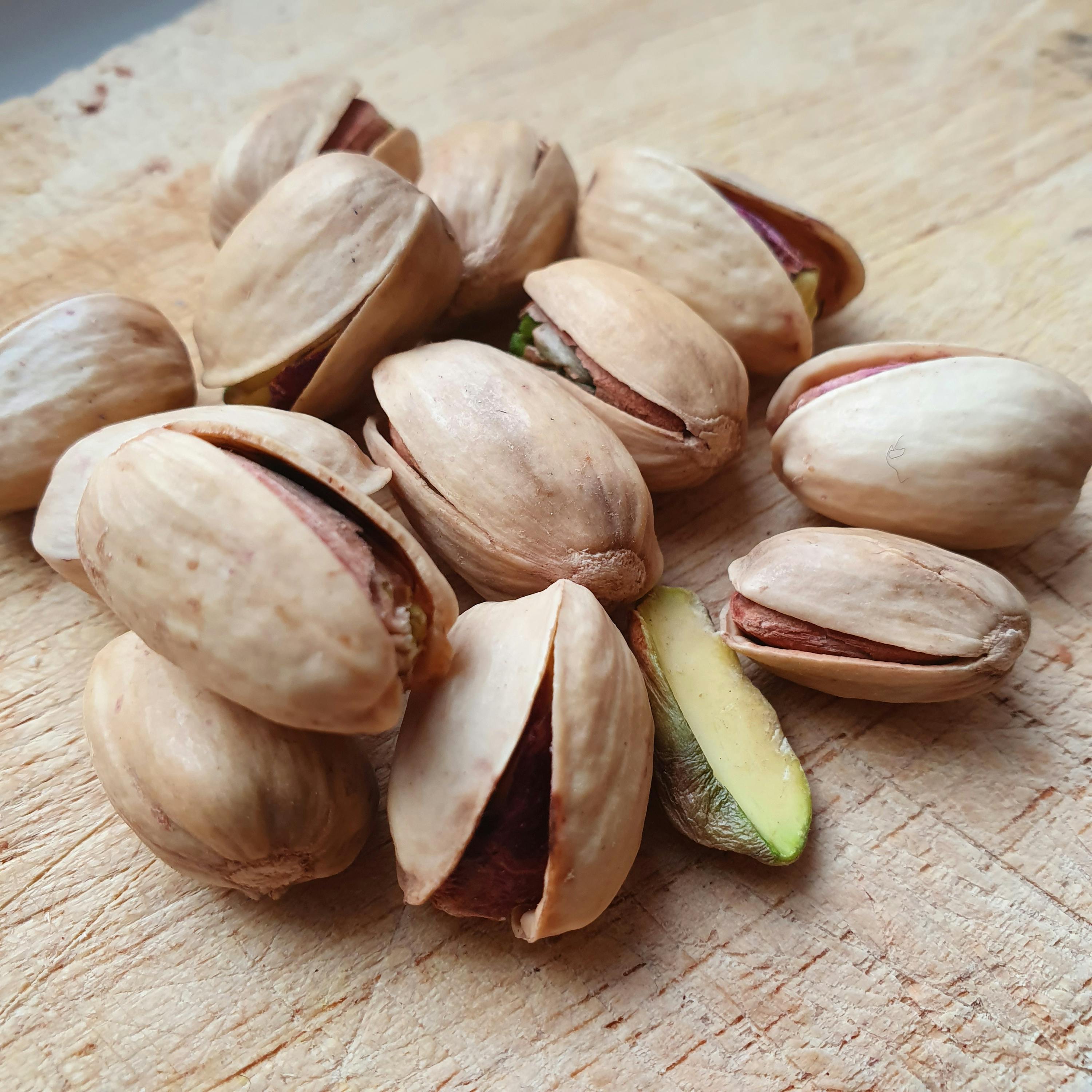 a pile of pistachios on a wooden surface