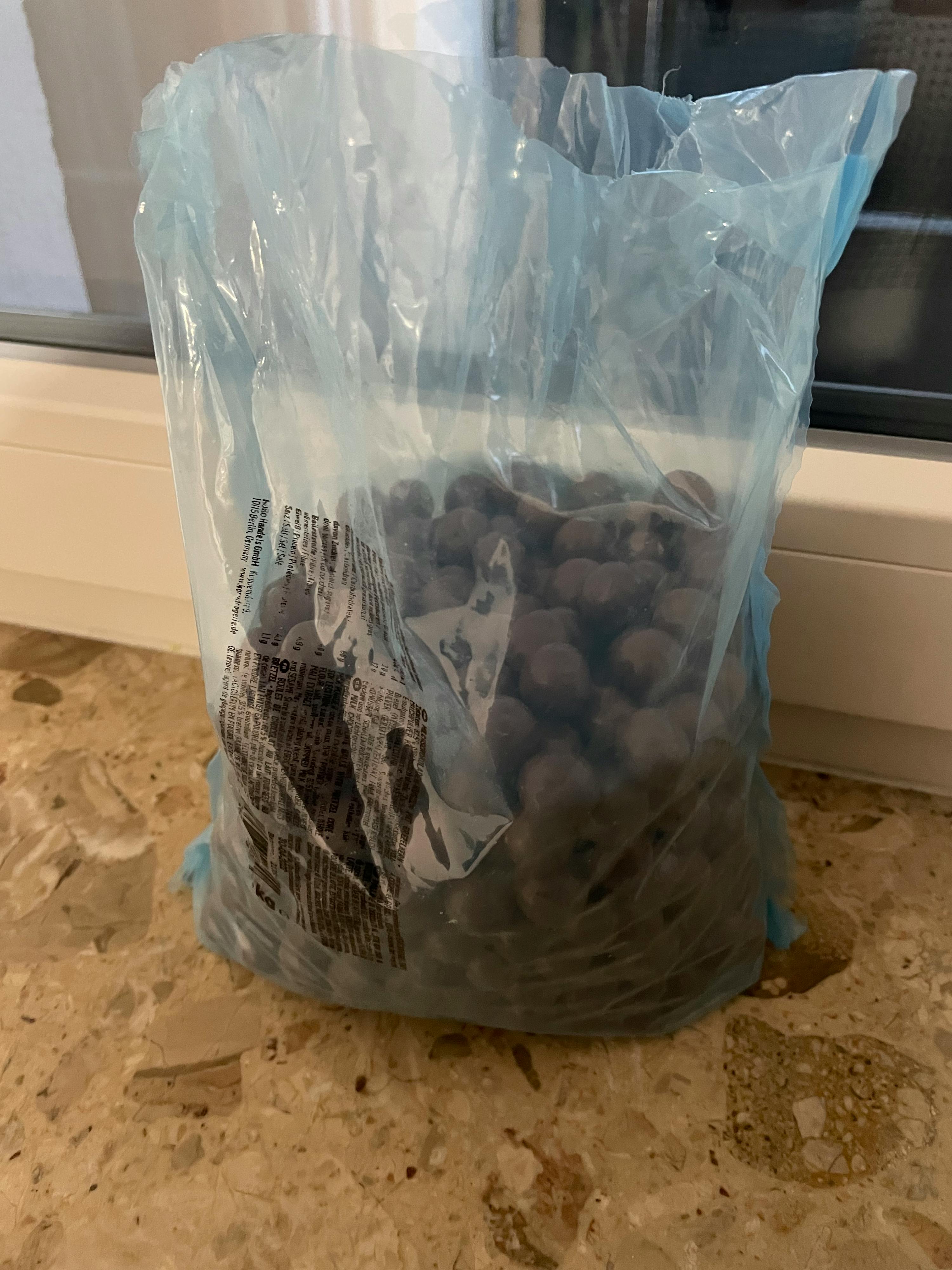 a blue plastic bag contains a lot of chocolate balls