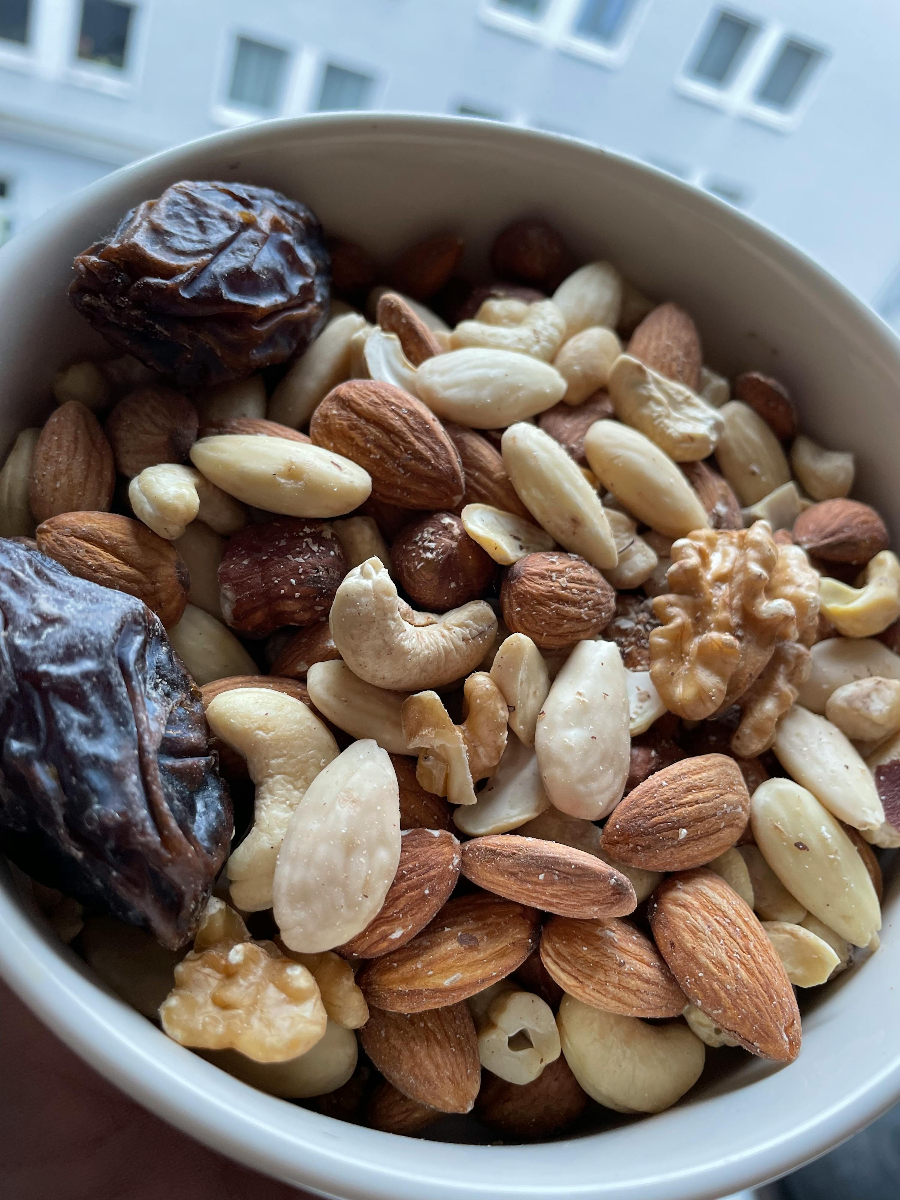 un bol rempli de noix et de dattes avec un bâtiment en arrière-plan