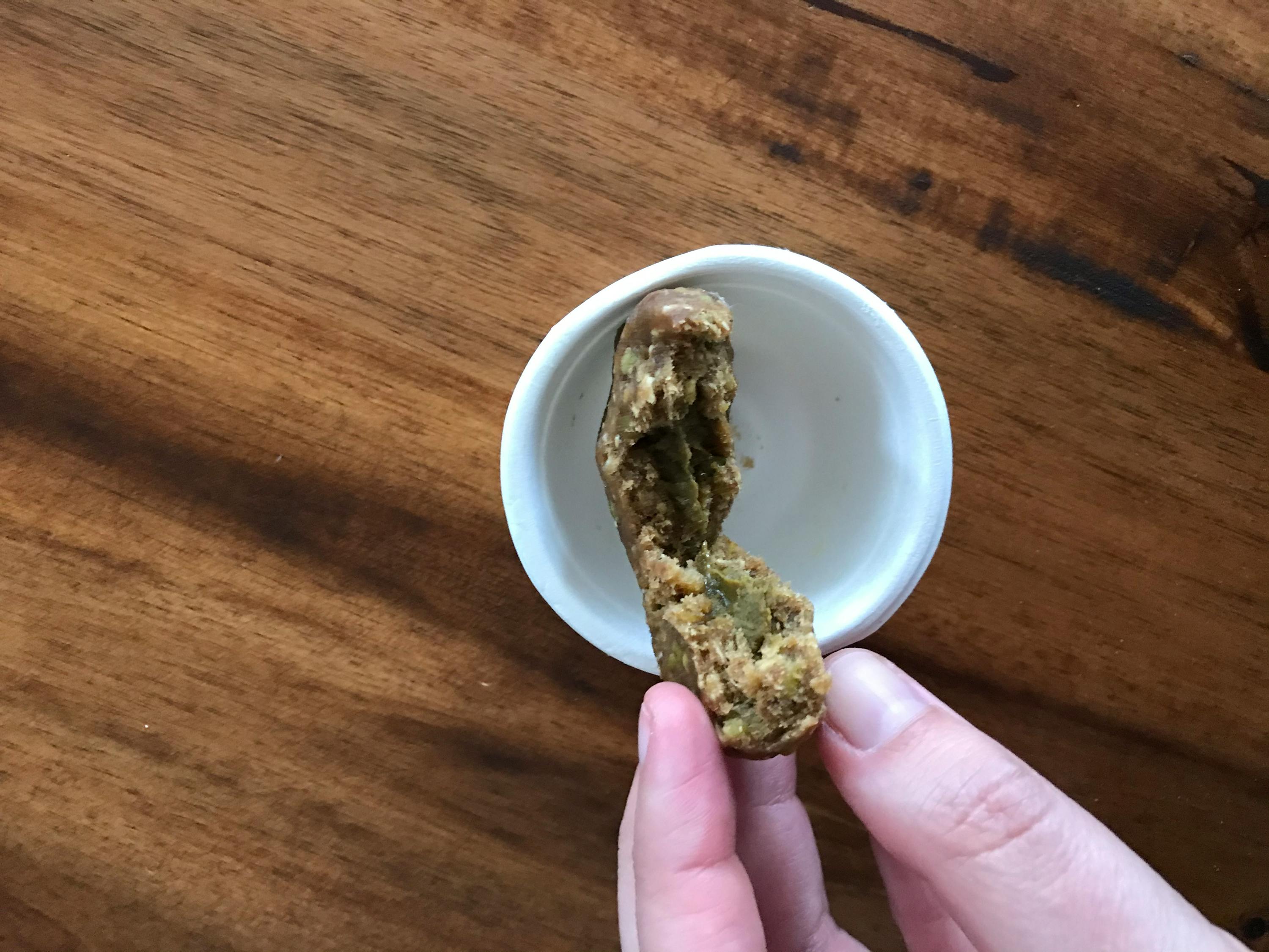 eine Person hält einen Keks in der Hand neben einer Tasse