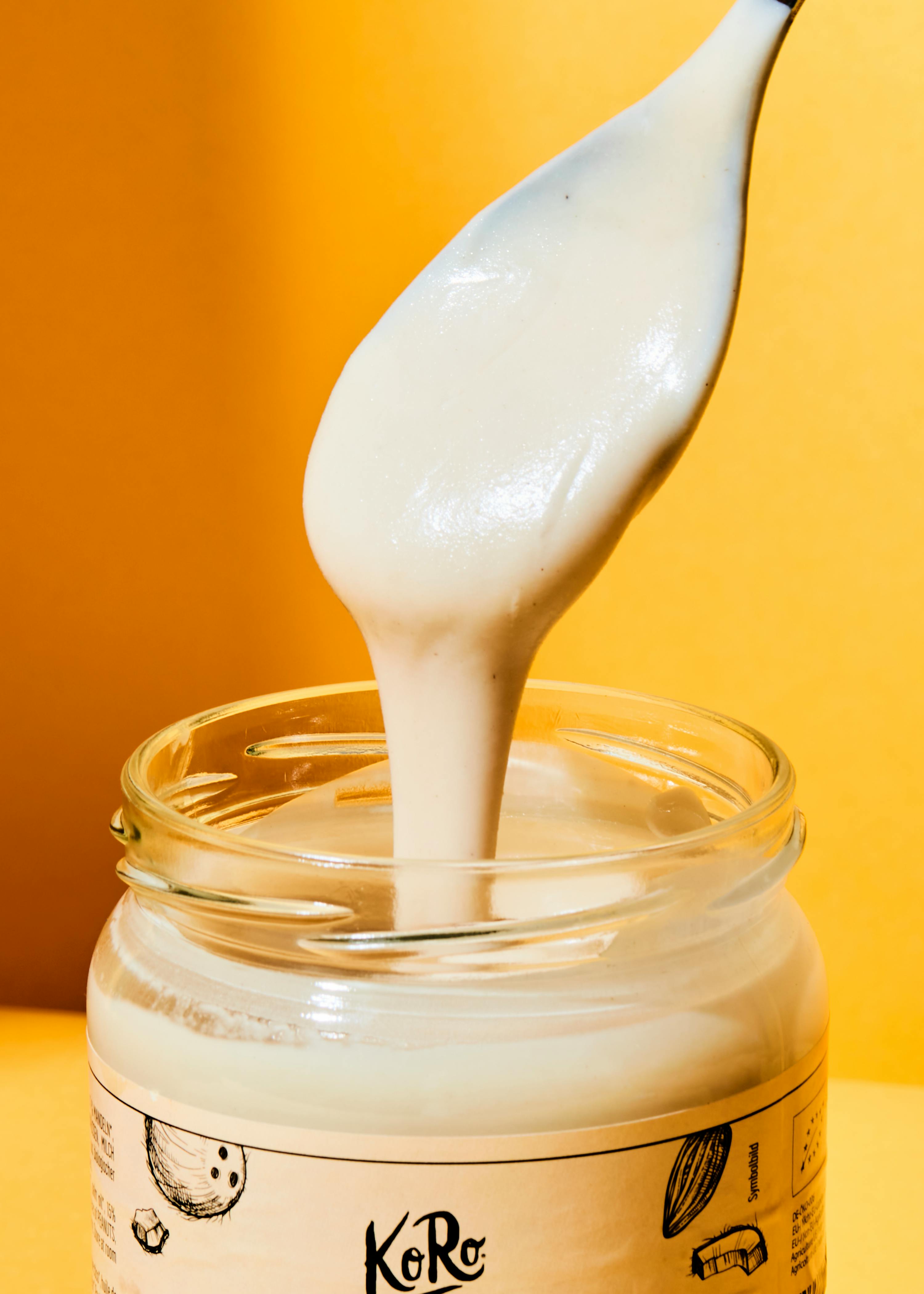 a spoon is pouring white liquid into a jar that says koro