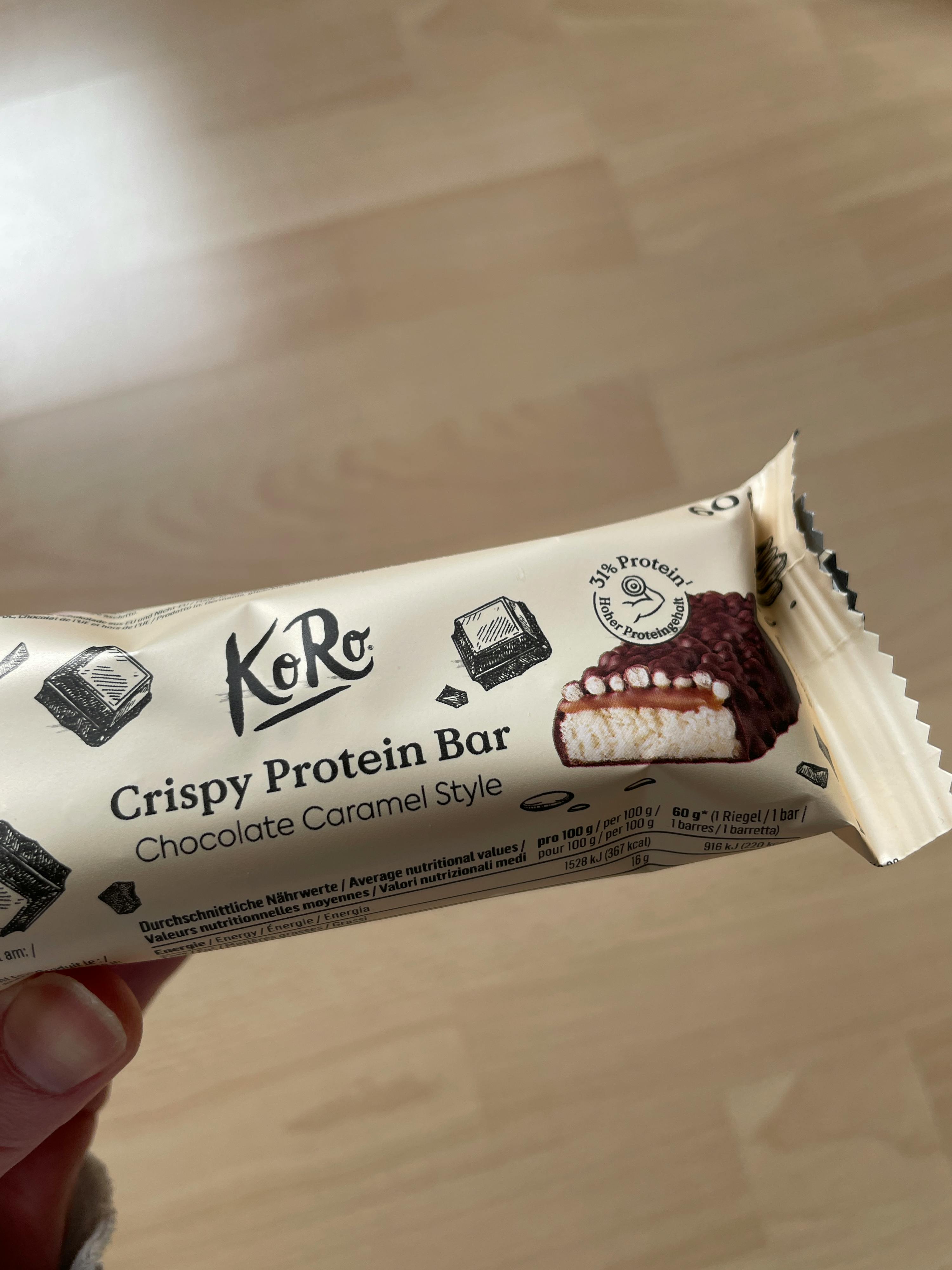 a person is holding a crispy protein bar chocolate caramel style