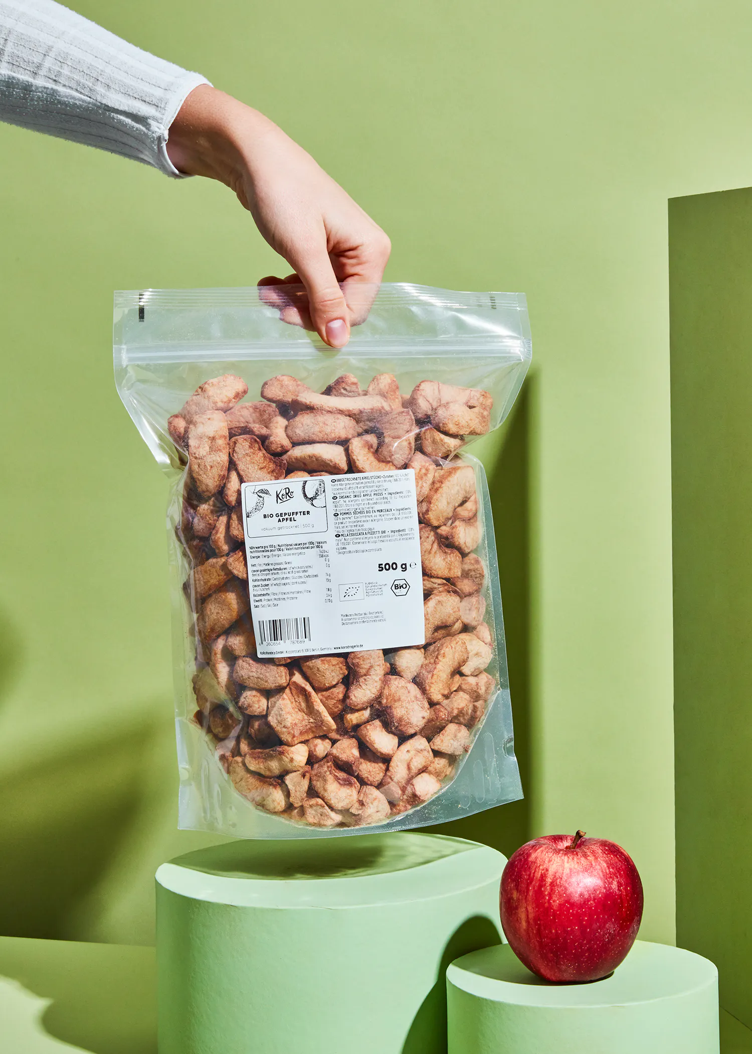 une personne tient un sac de pommes séchées à côté d' une pomme rouge