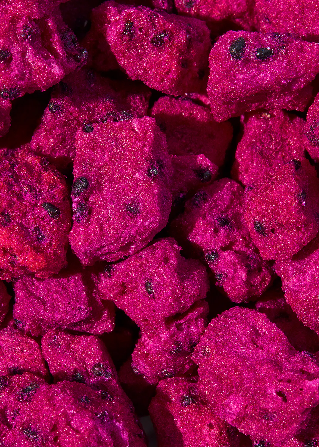 un tas de roches roses avec des graines noires