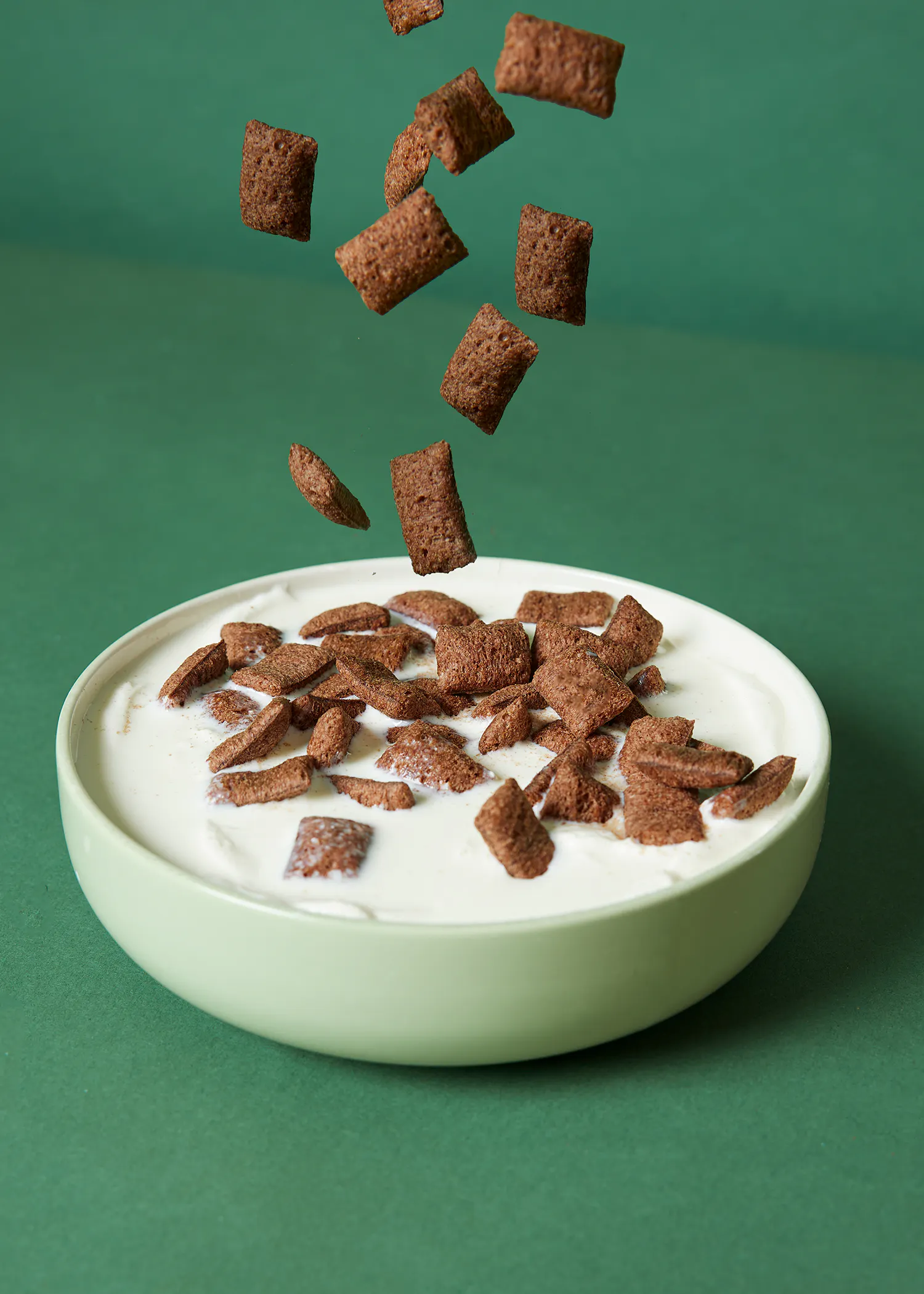 a bowl of cereal with chocolate pieces falling into it