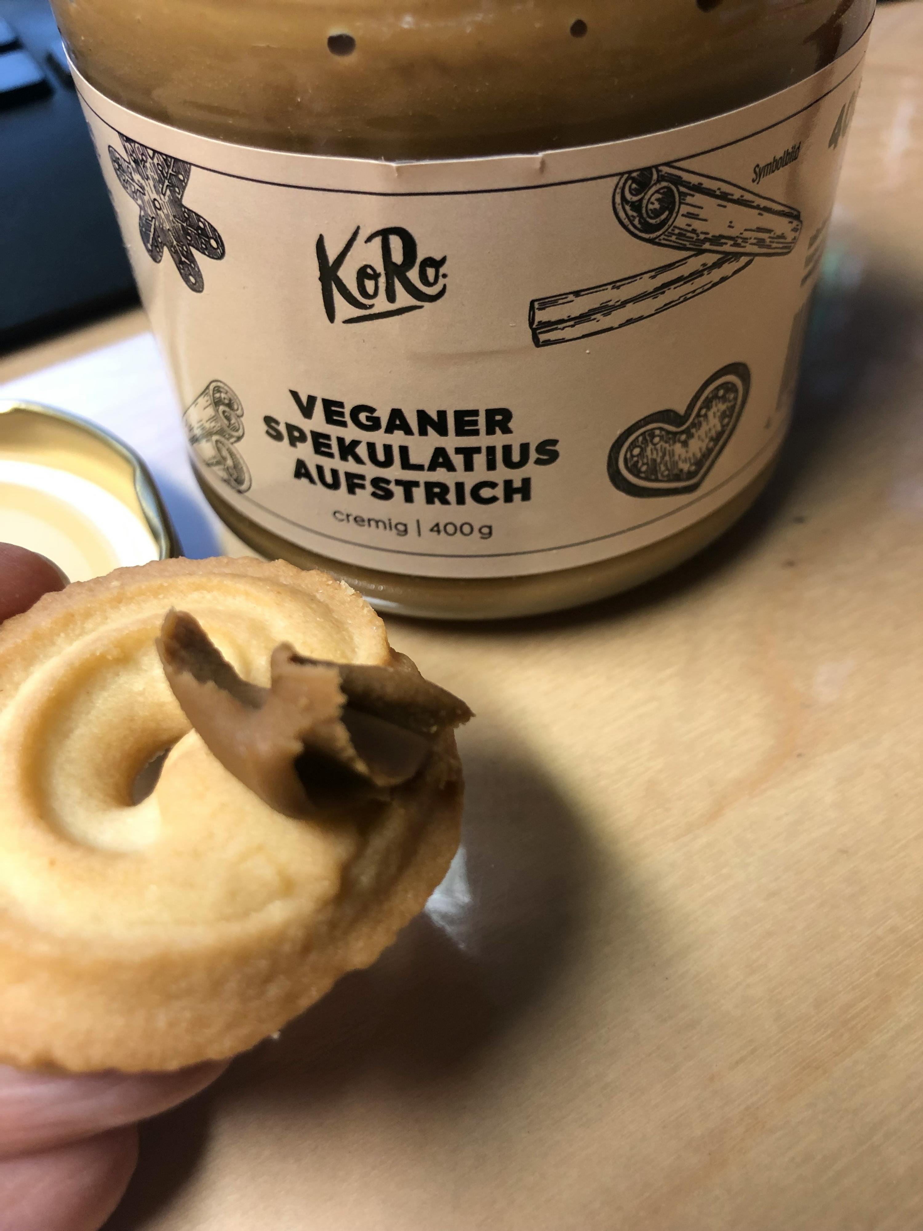 a person is holding a cookie next to a jar of veganer speculatius aufstrich