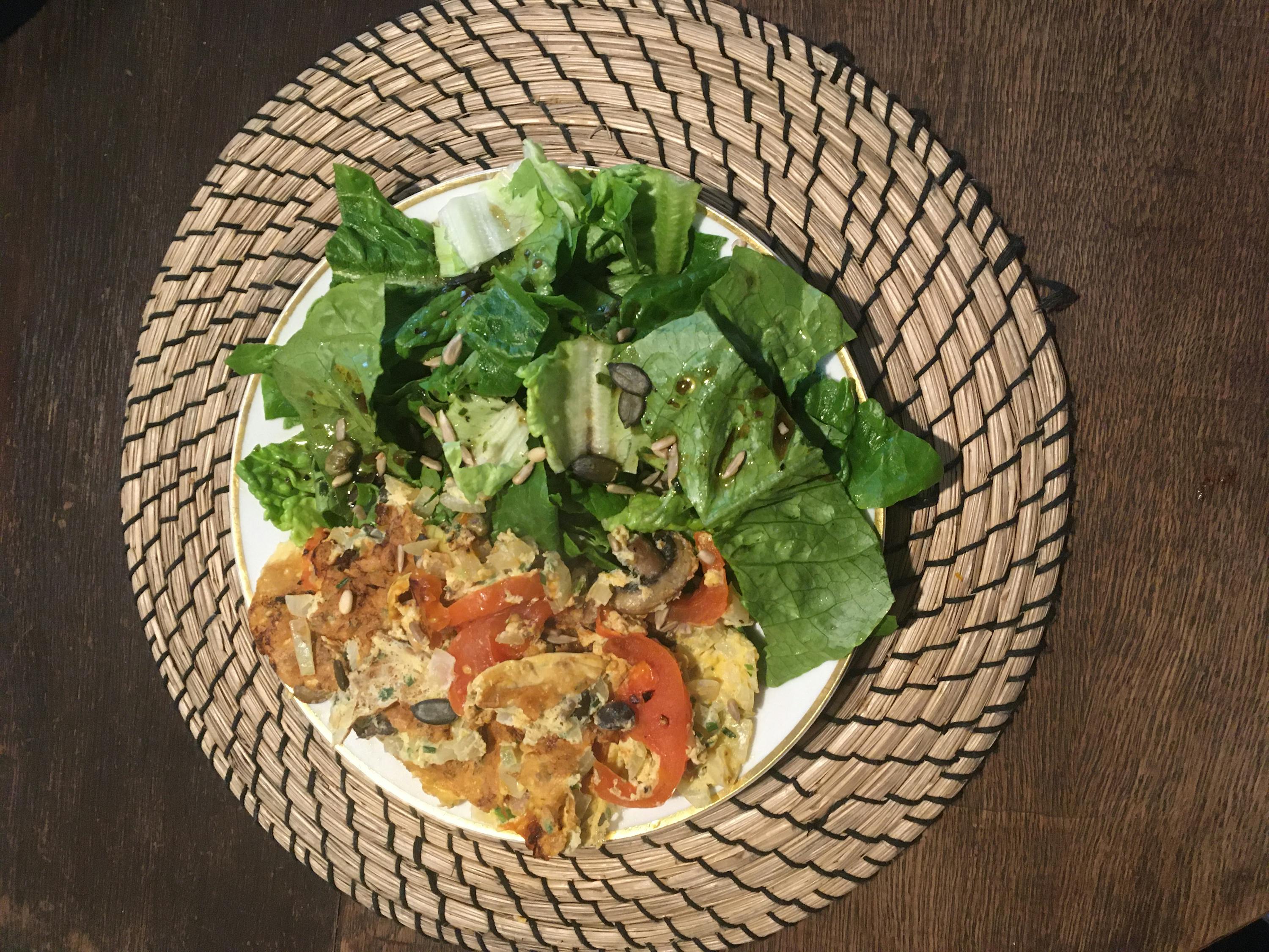 a plate of food with lettuce and tomatoes on a placemat