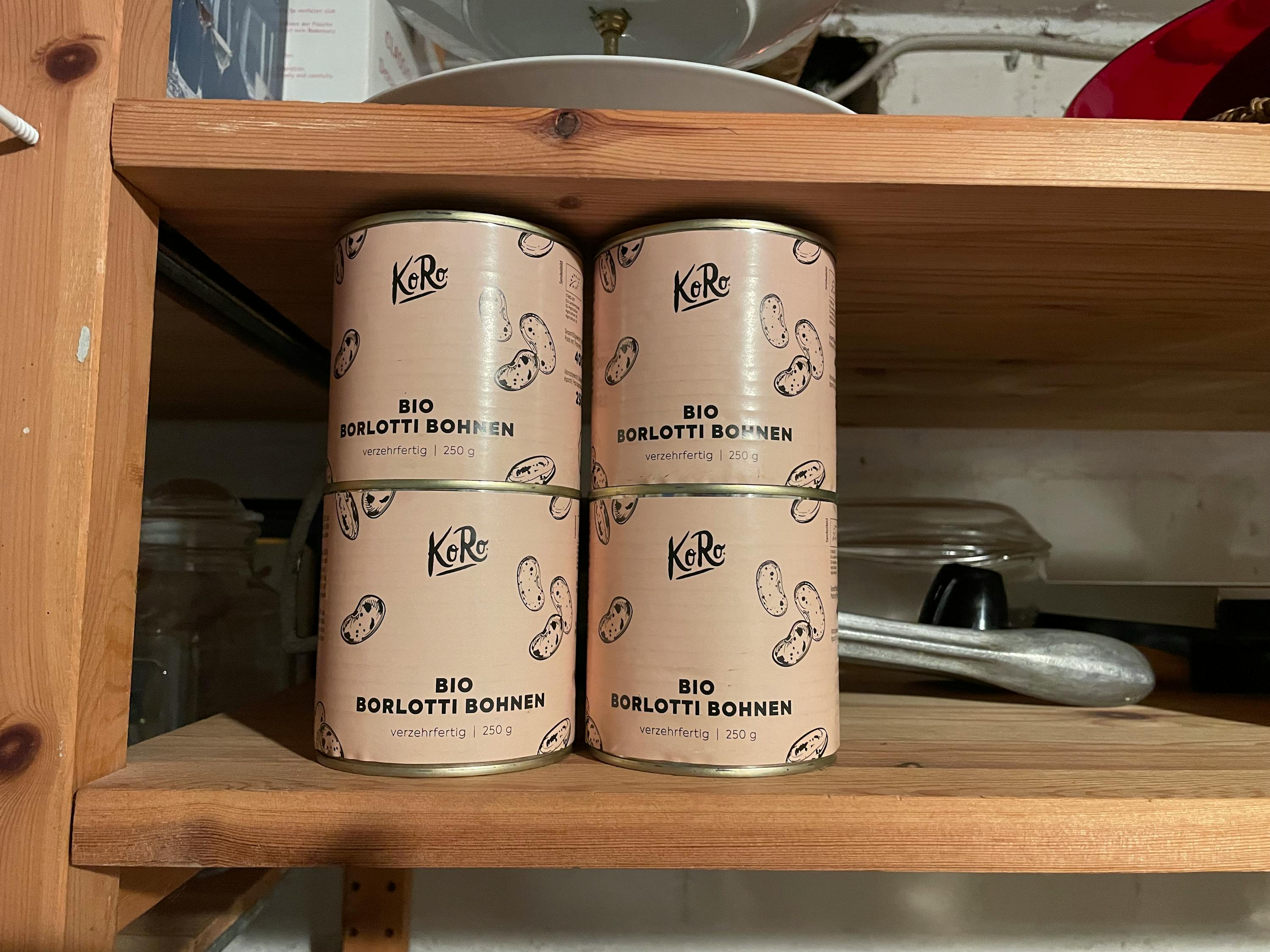 vier Dosen bio borlotti Bohnen stehen auf einem Holzregal