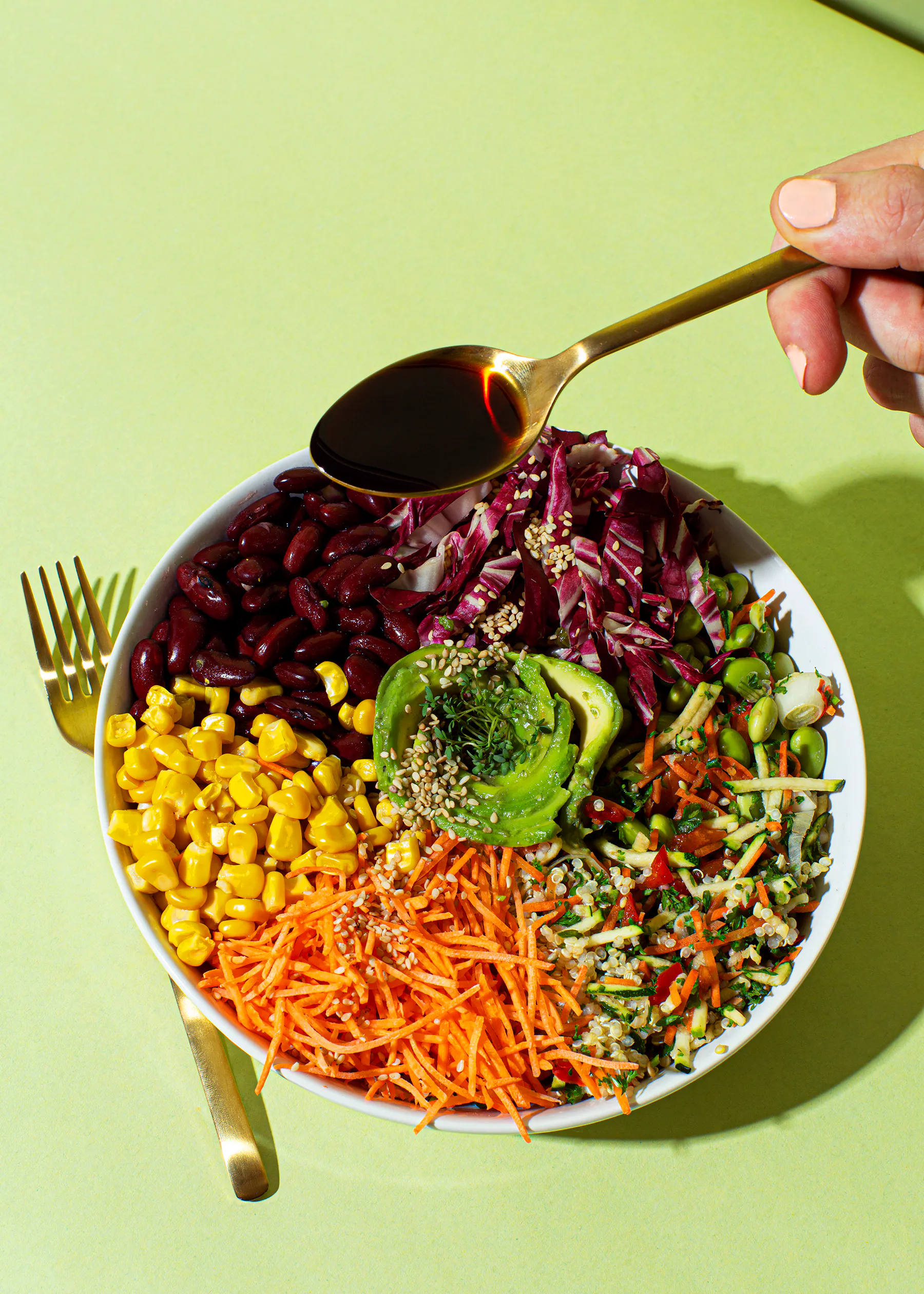 a person is pouring sauce on a salad with a fork