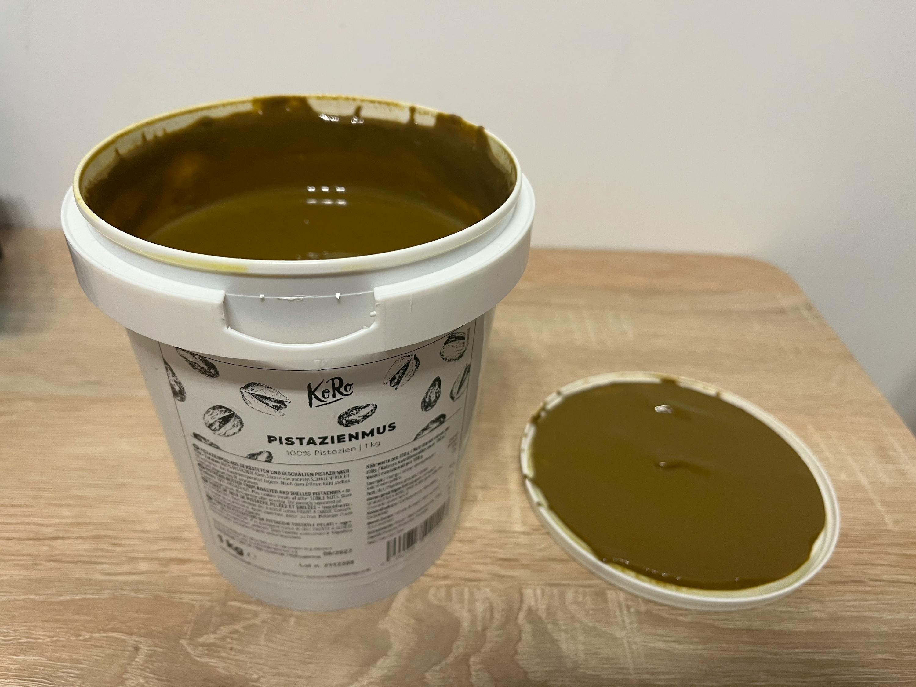 un seau de pistazienmus est assis sur une table en bois