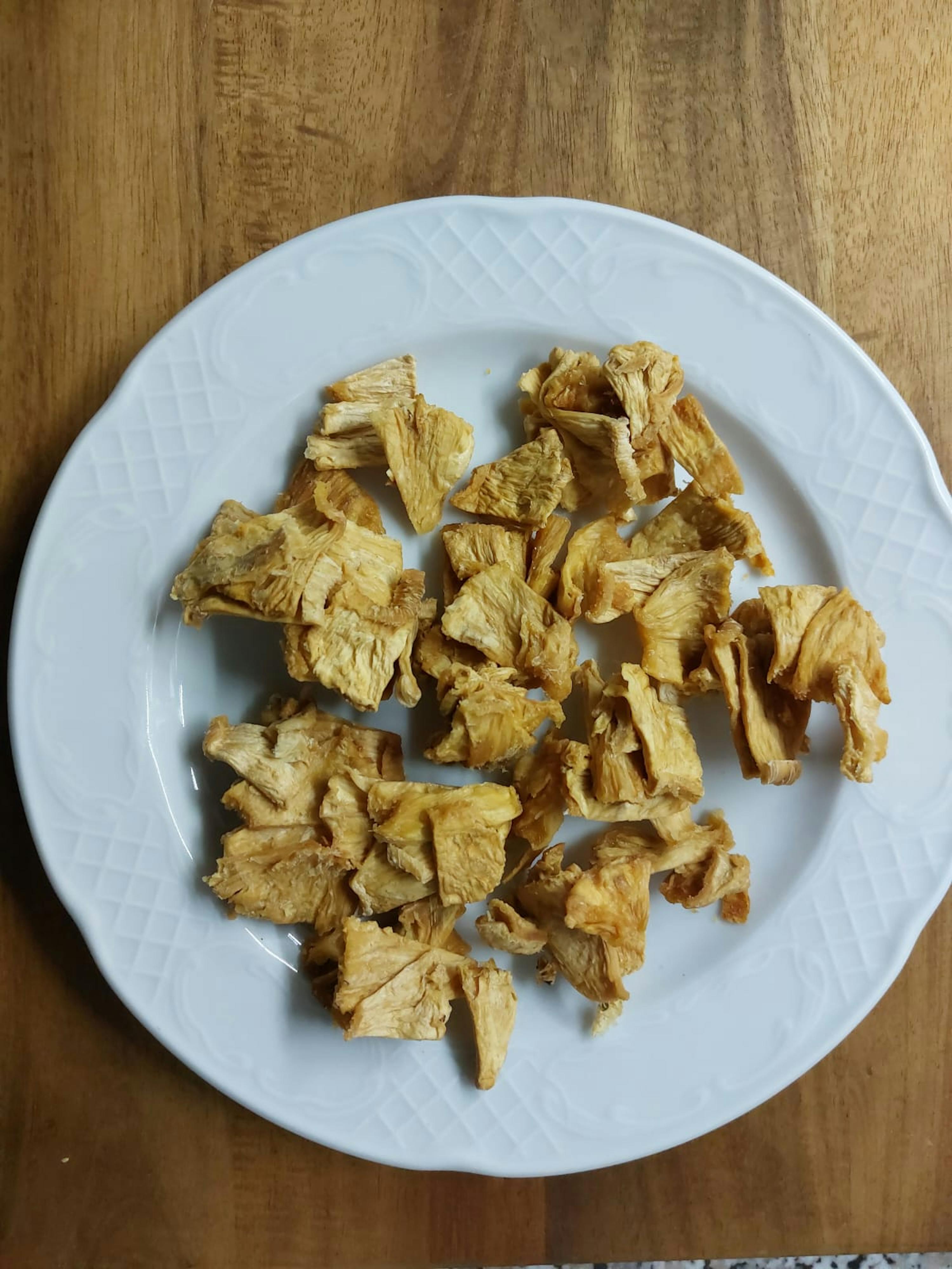 ein weißer Teller mit getrockneten Pilzen auf einem Holztisch