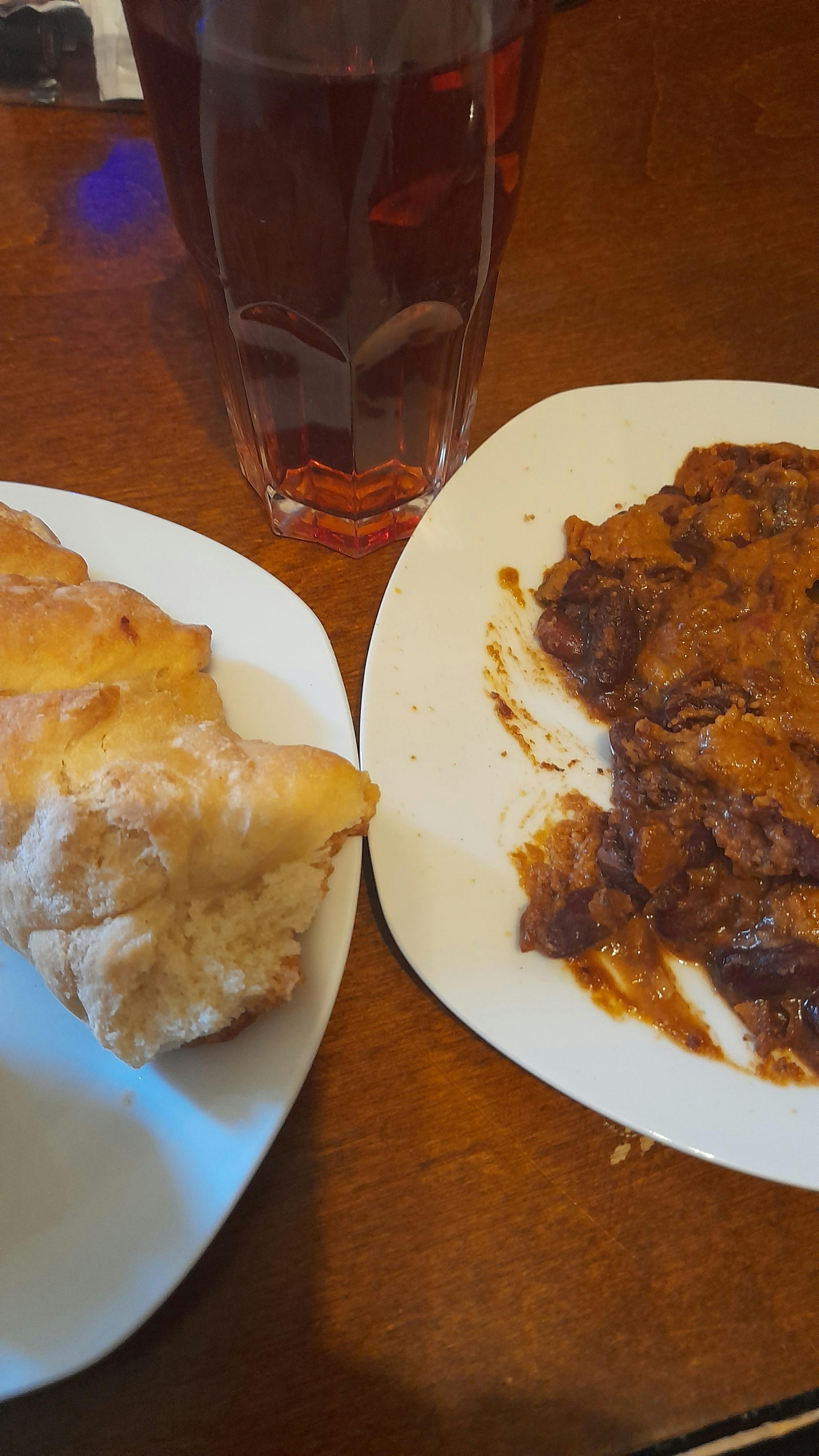 two plates of food on a table with a glass of red liquid