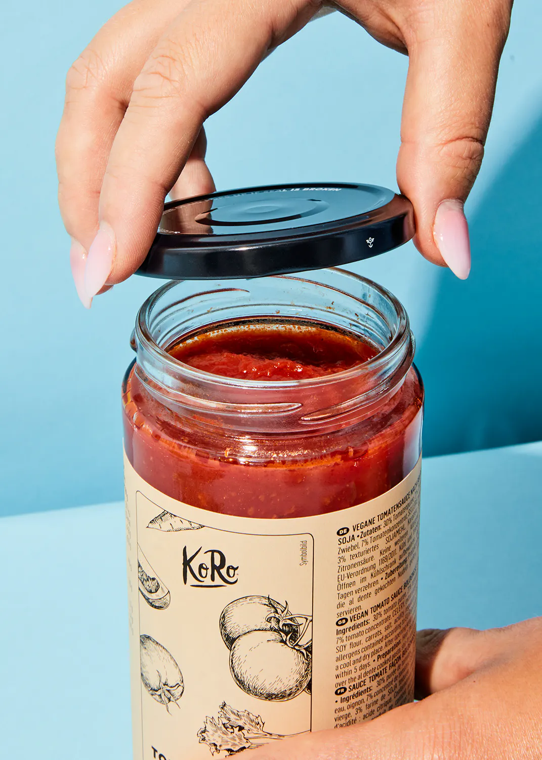 eine Person öffnet ein Glas mit Tomatensauce mit der Aufschrift " vegane Tomatensauce "