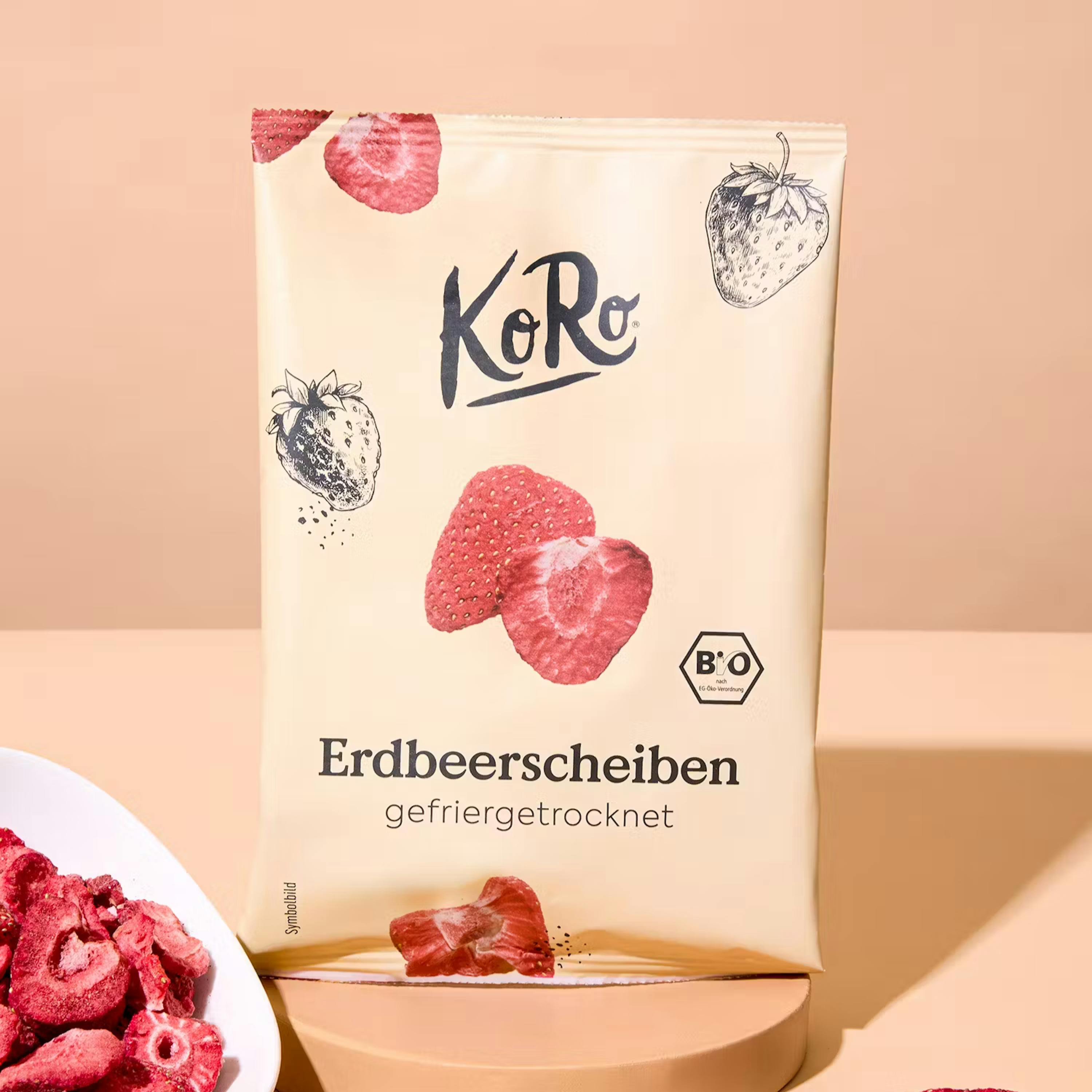 un sachet beige de tranches de fraises lyophilisées koro avec un logo bio et un bol de fraises lyophilisées à côté.