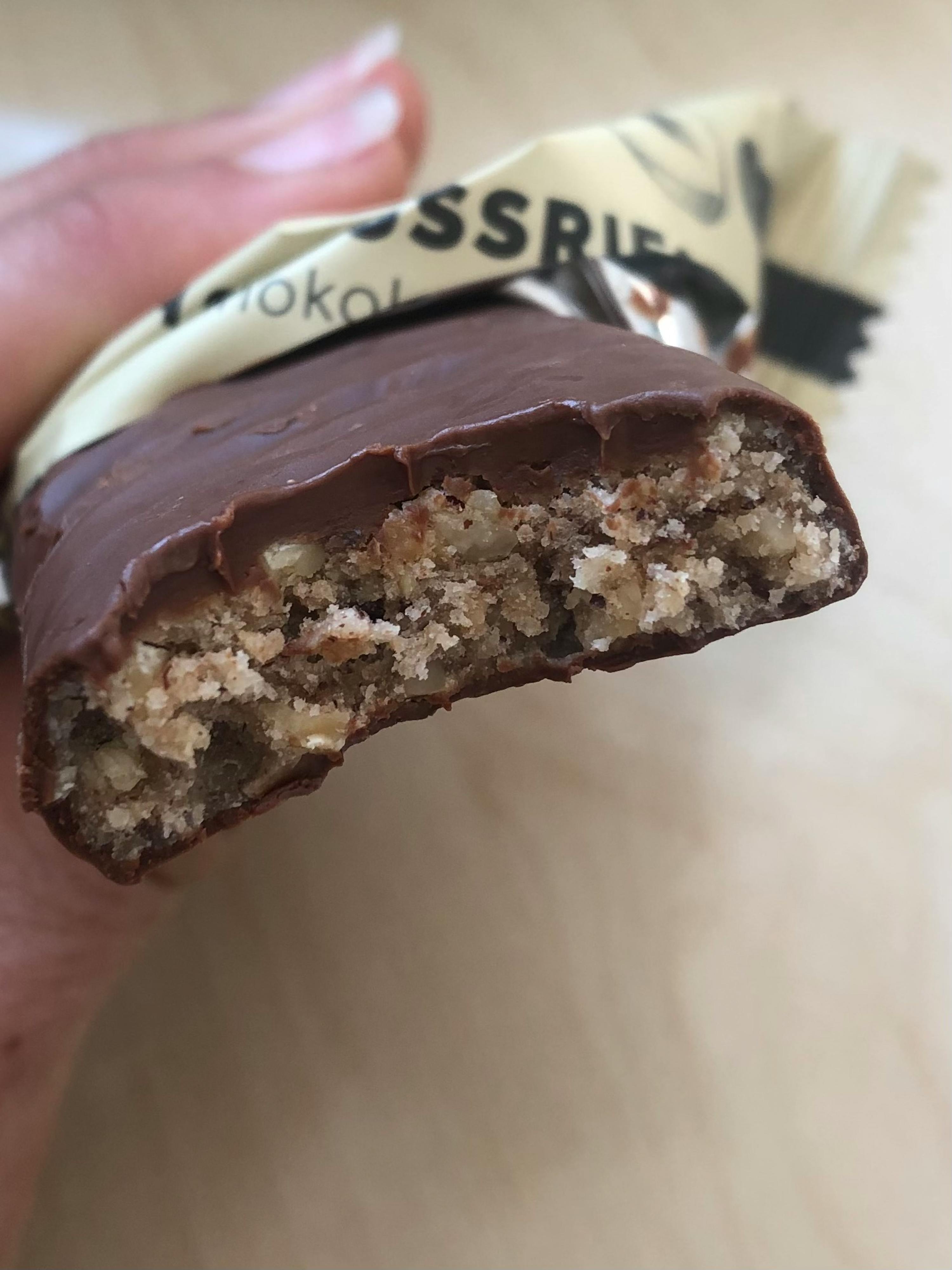 une personne tient une barre de chocolat avec une bouchée sortie