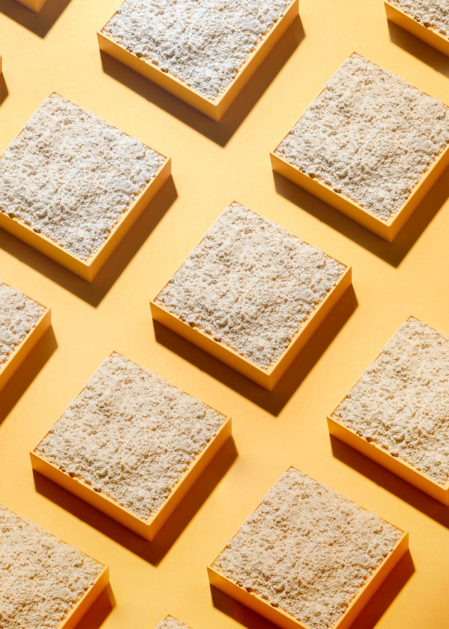 a row of squares with powdered sugar on them on a yellow background