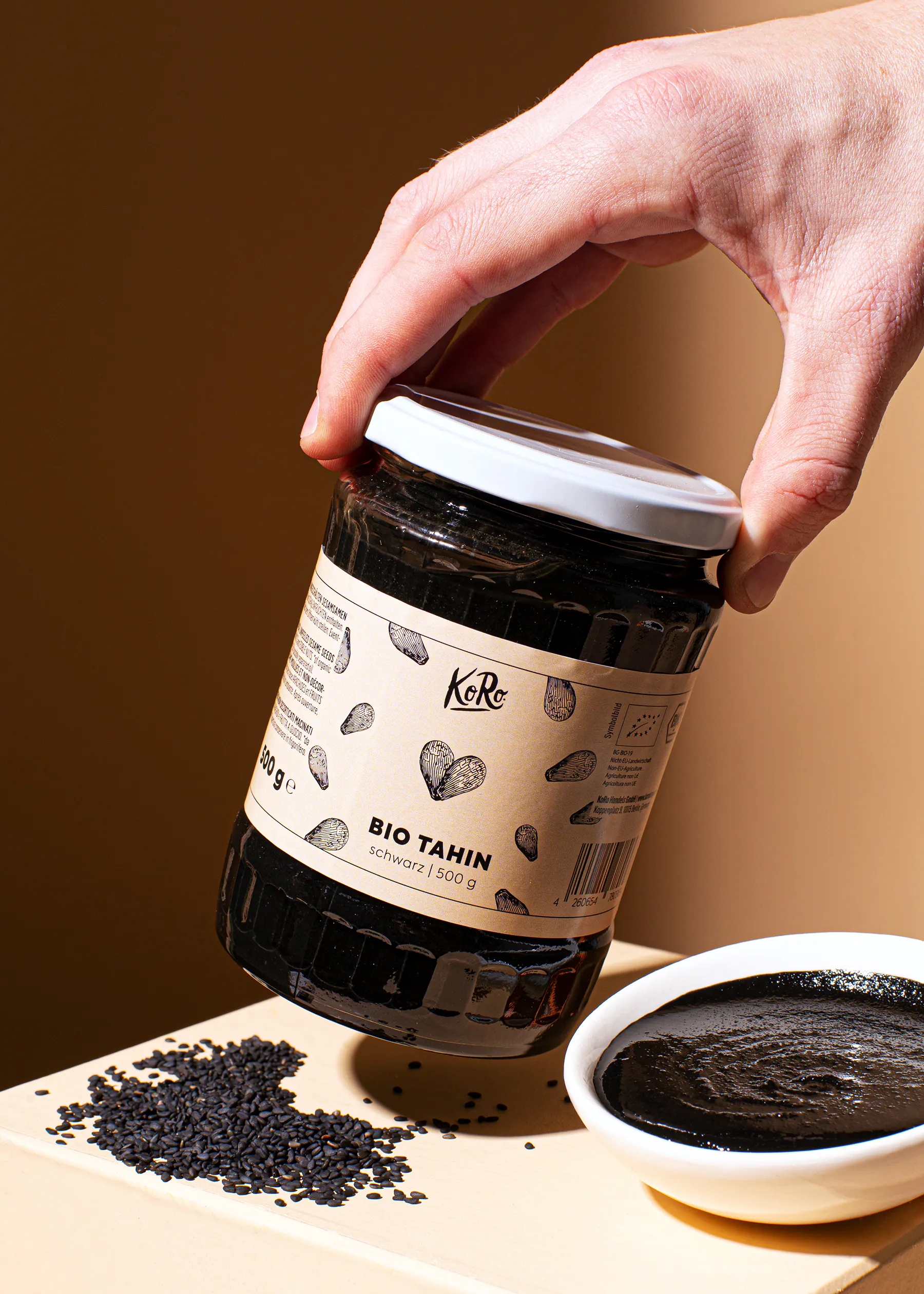 Eine Person hält ein Glas Bio-Tahin in der Hand