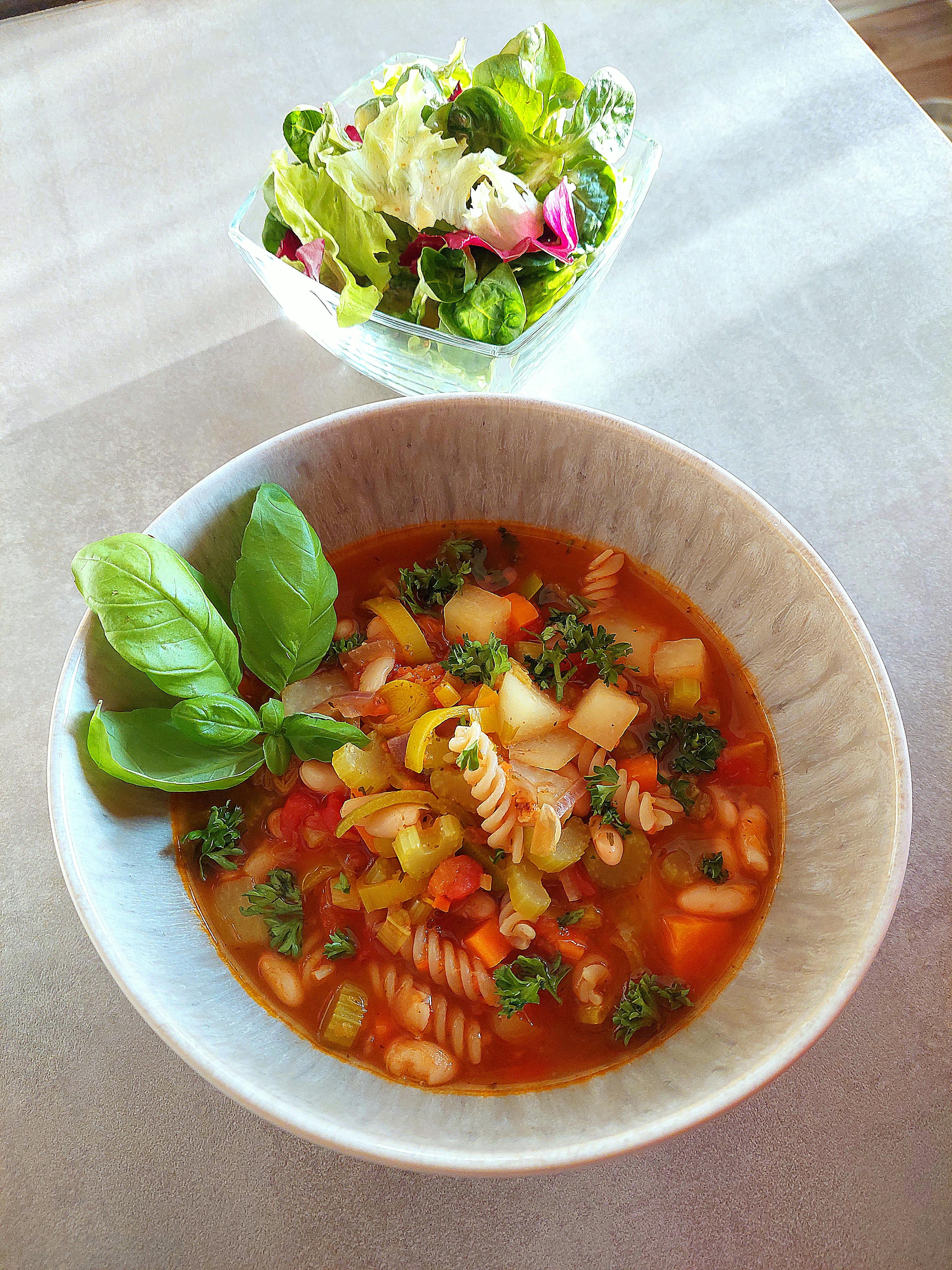 una ciotola di zuppa e una ciotola di insalata sono su un tavolo
