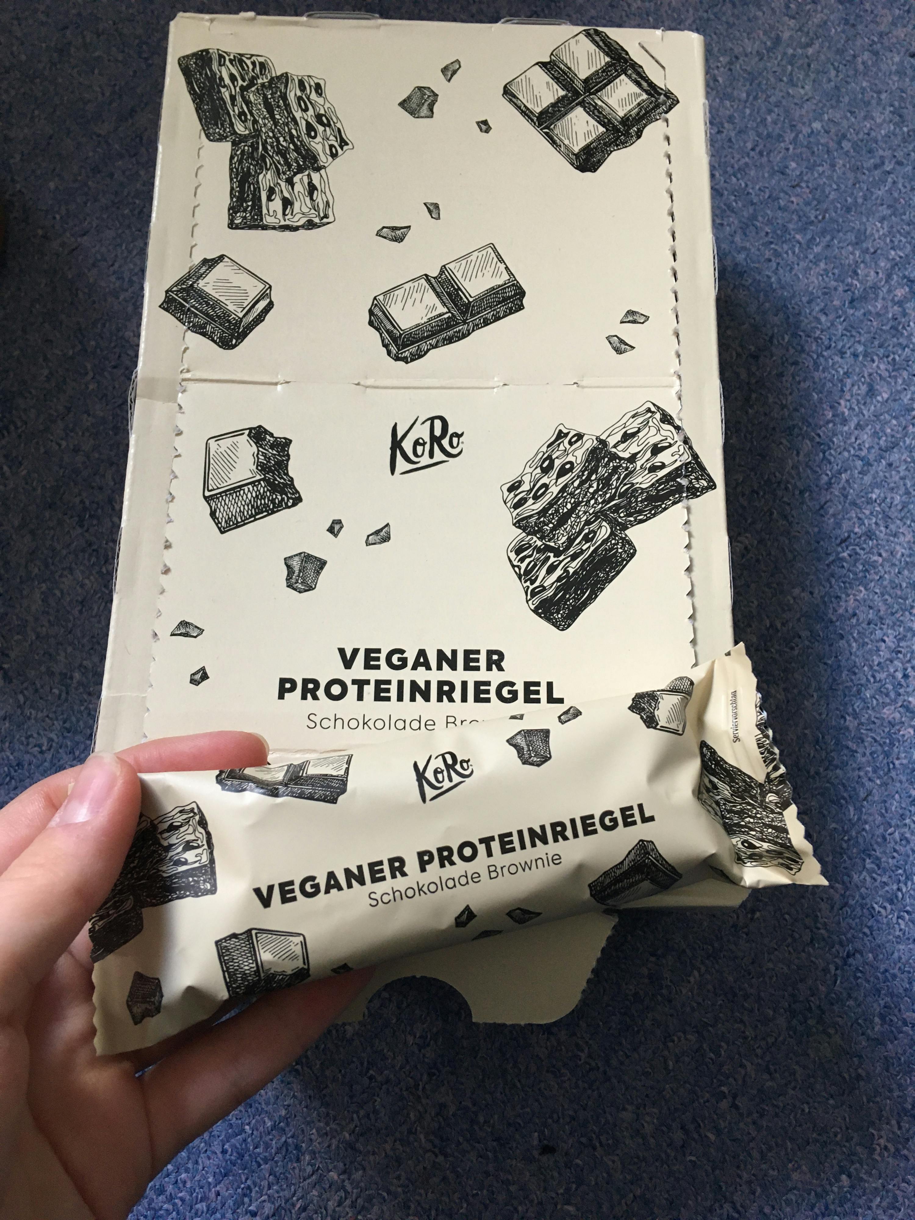a person is holding a package of veganer proteinriegel
