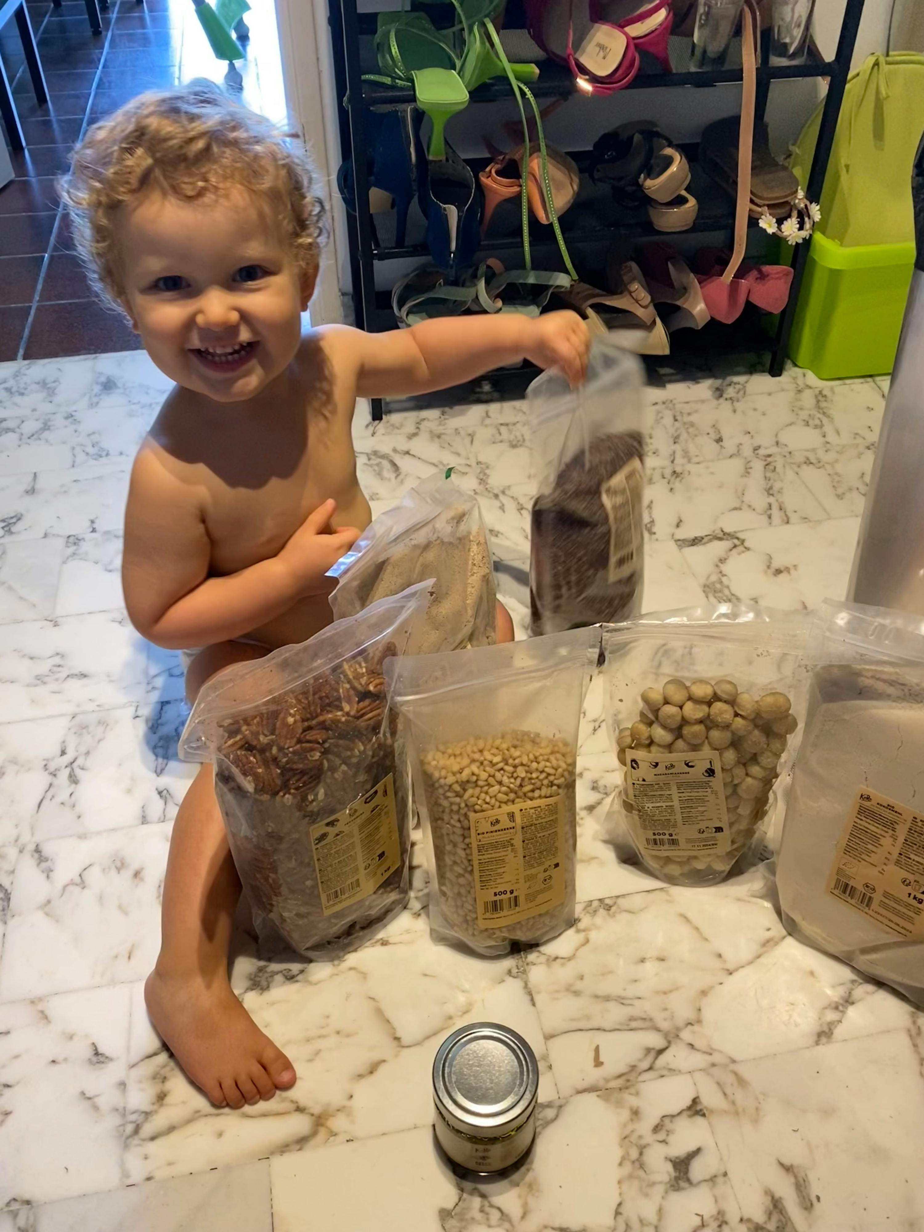 un bambino è seduto su un pavimento di marmo accanto a un mucchio di cibo